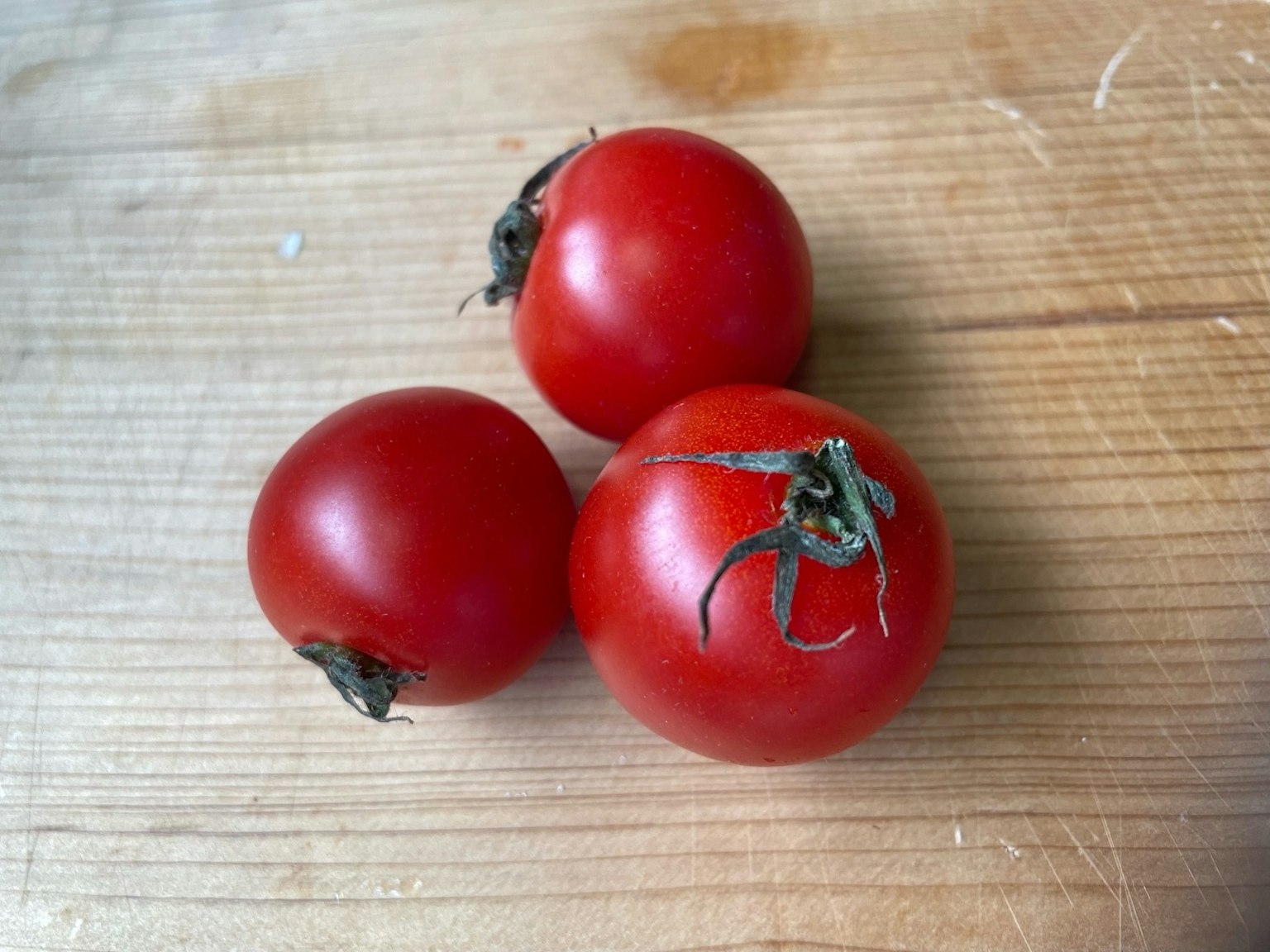 Three red tomatoes on a wooden table
