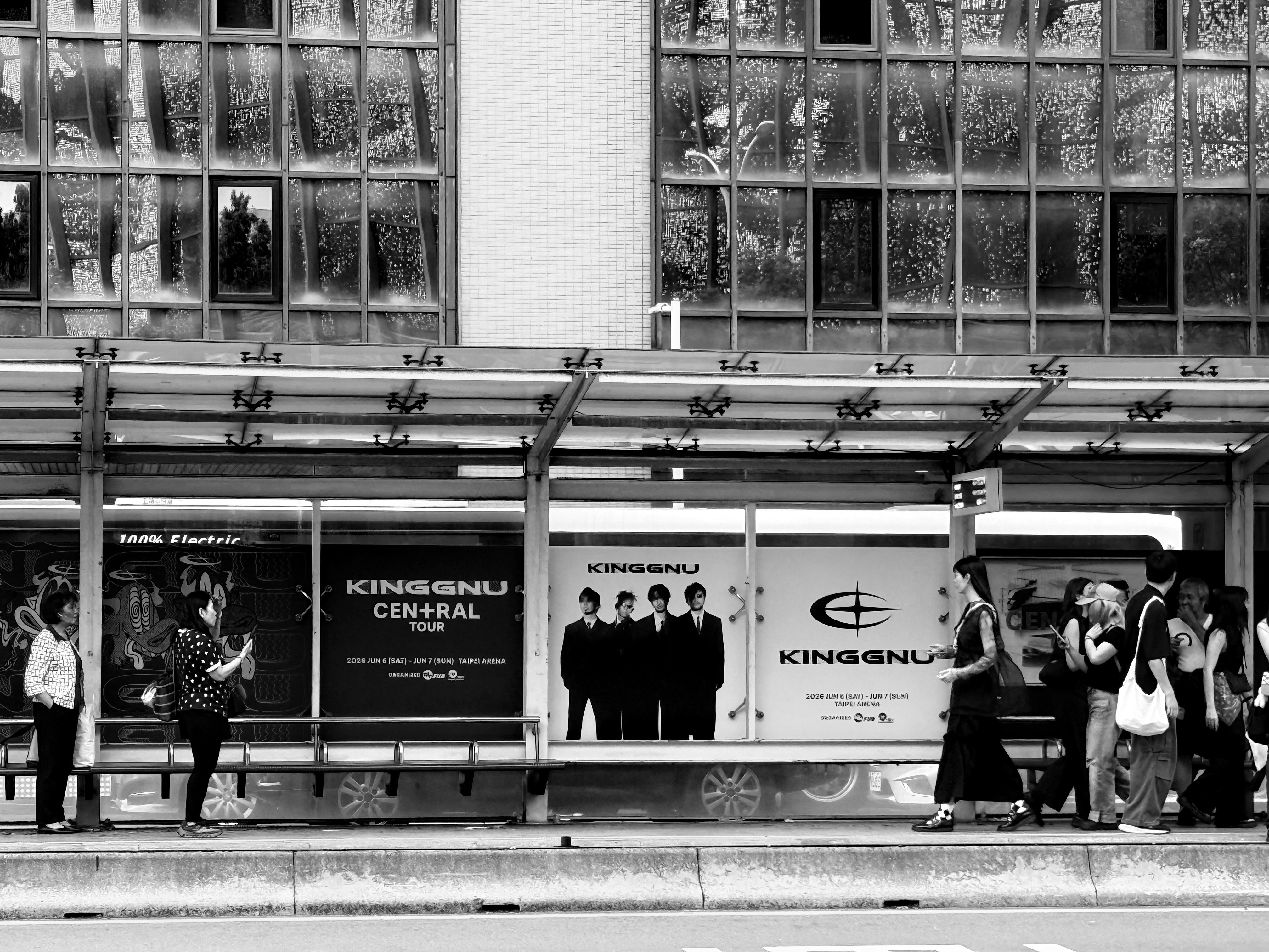 駅のホームでベンチに座る人々と広告パネルのある待合スペース