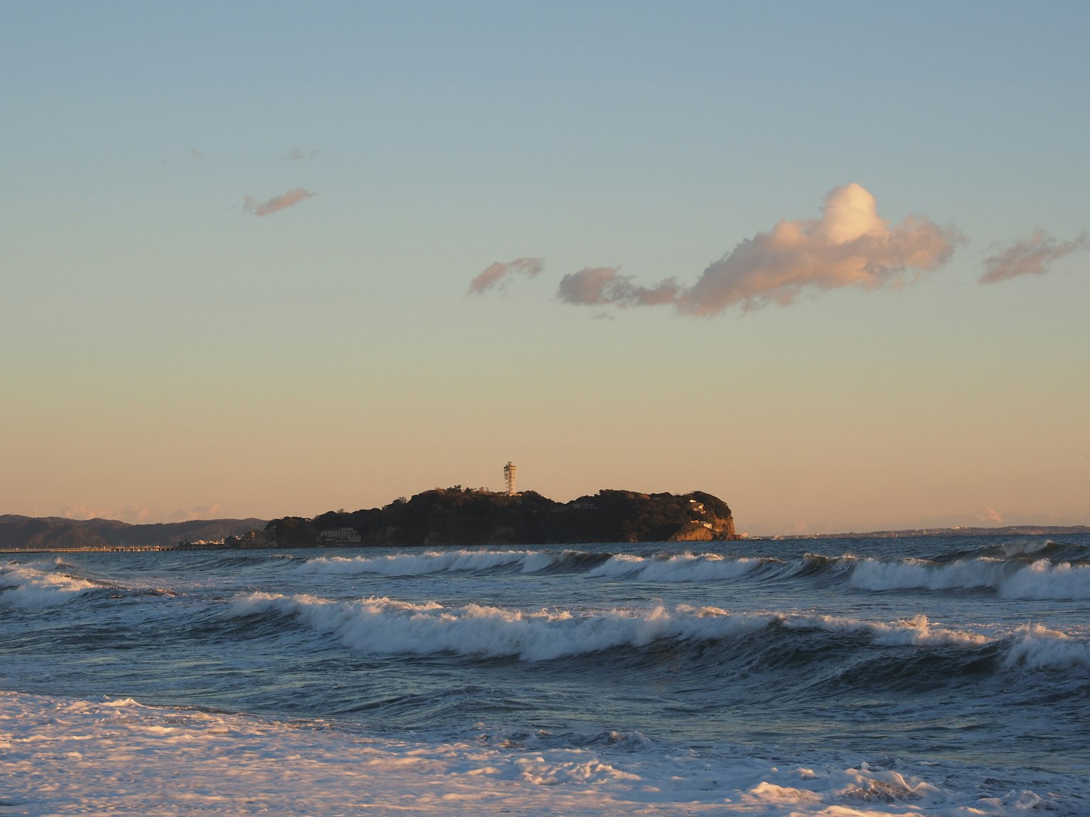Onde che si infrangono sulla riva con un'isola piccola in lontananza
