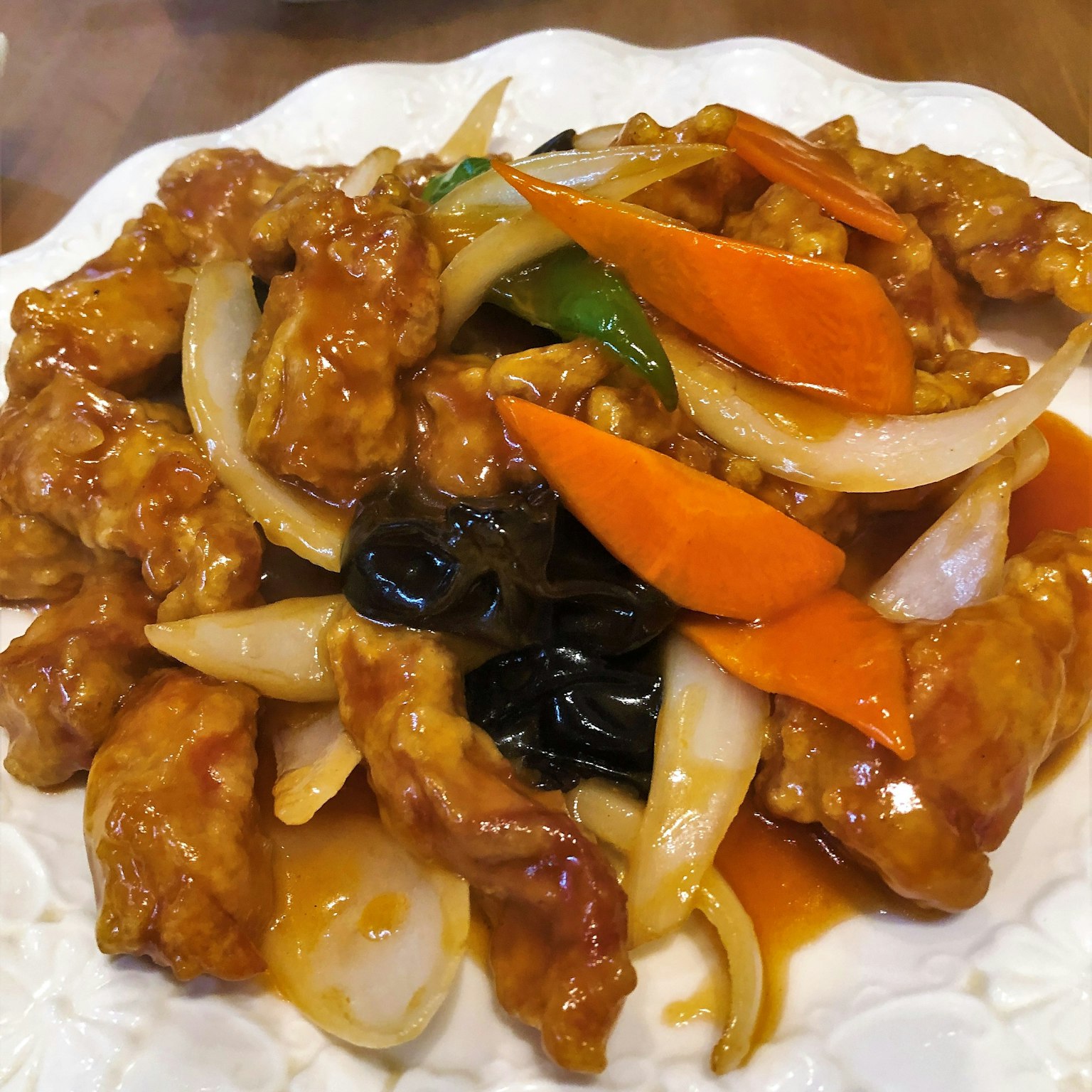 Sweet and sour chicken dish with sliced carrots and onions on top