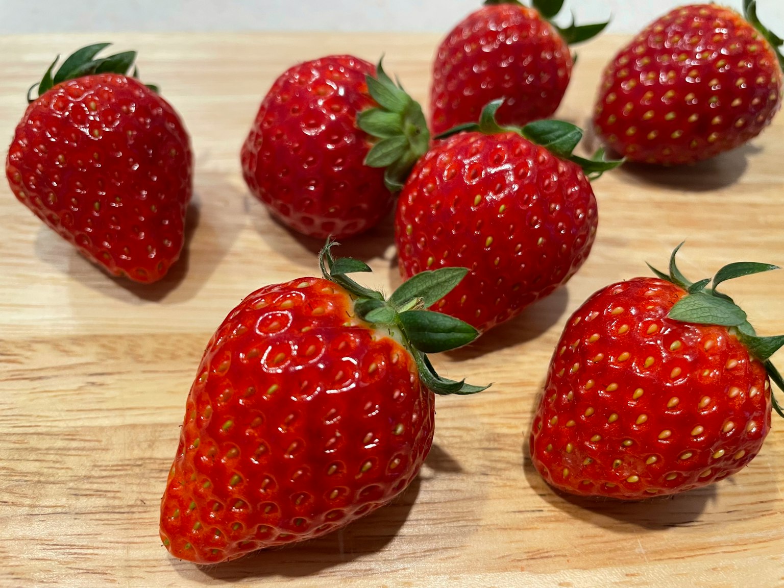 Fresh strawberries arranged on a wooden board