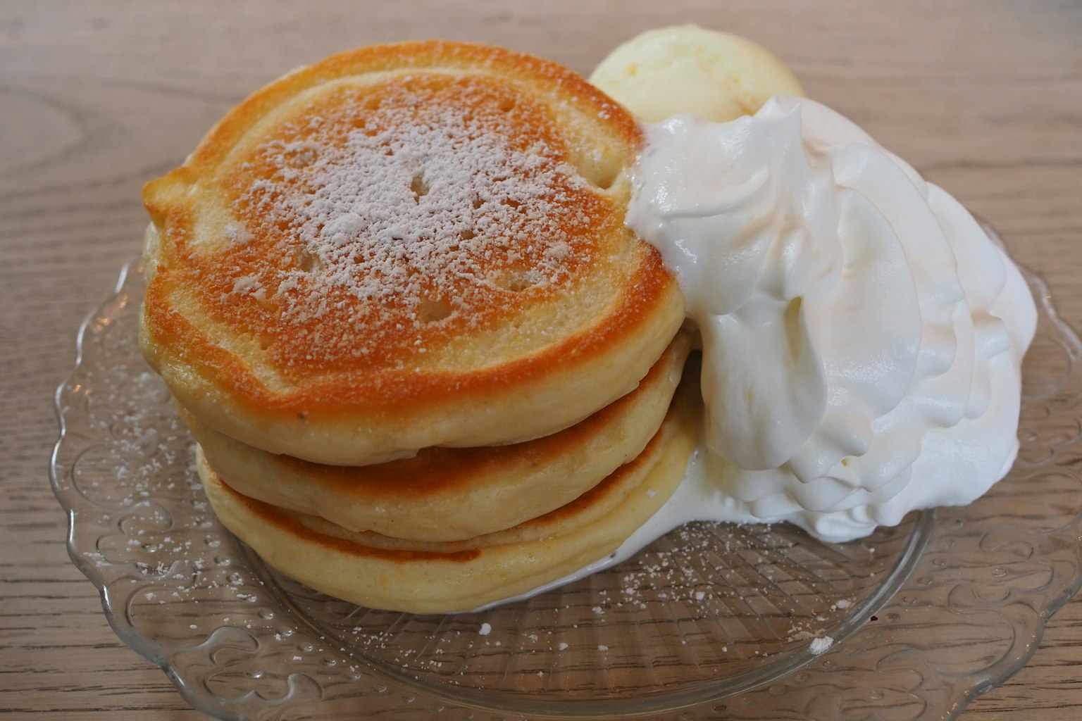 Tre pancake soffici impilati con panna montata e burro a lato