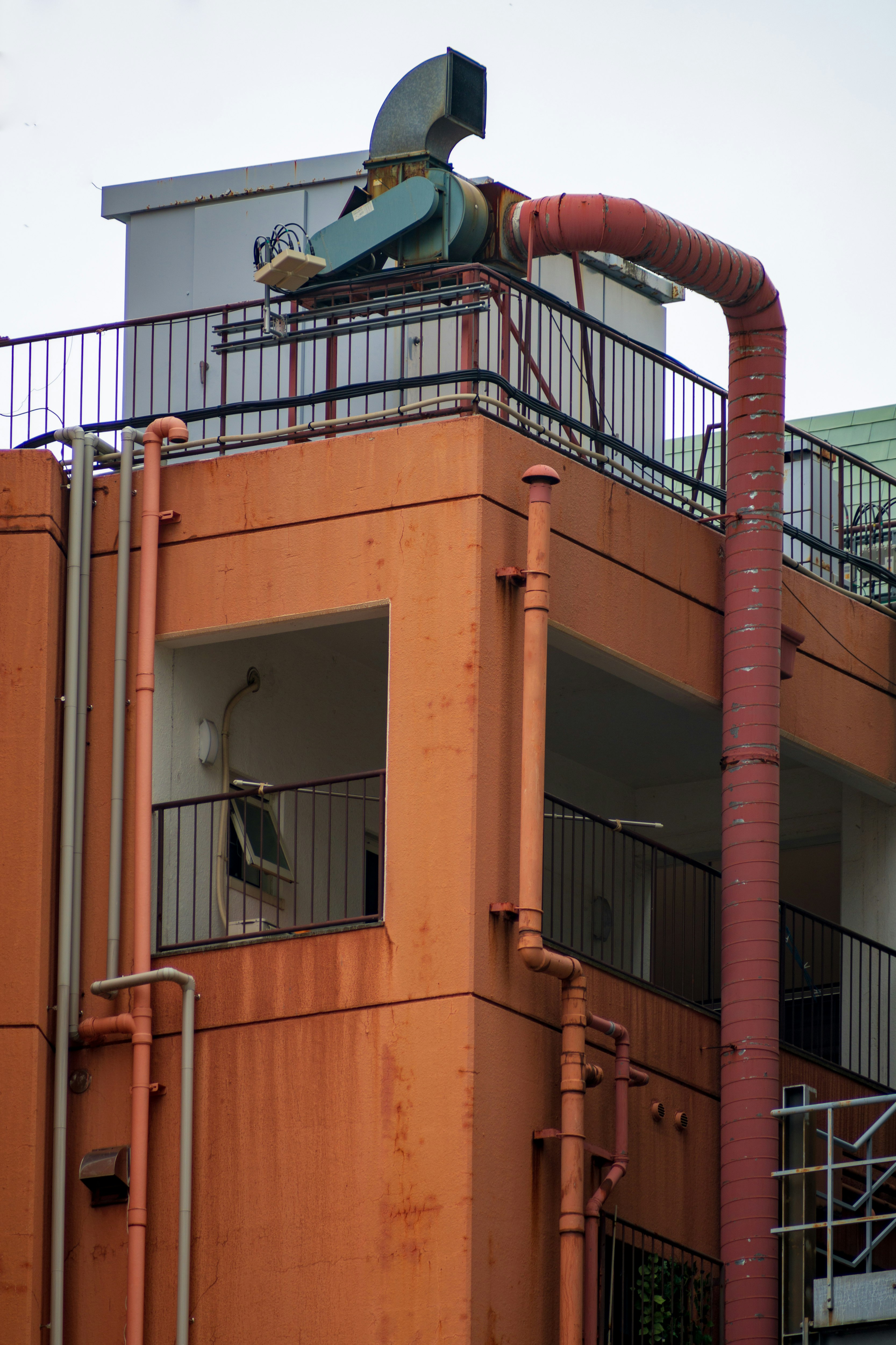 exterior of an industrial facility with rust-colored smokestack and pipes