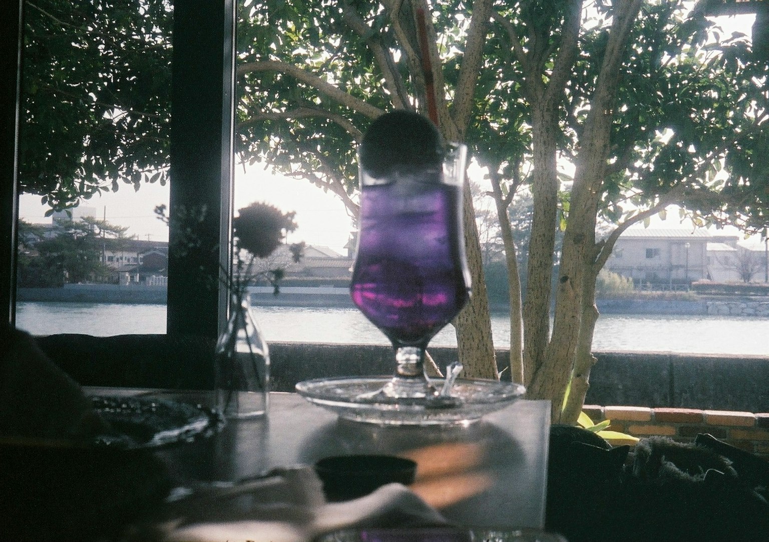 Lila Cocktail auf einem Tisch mit Blick auf den Fluss