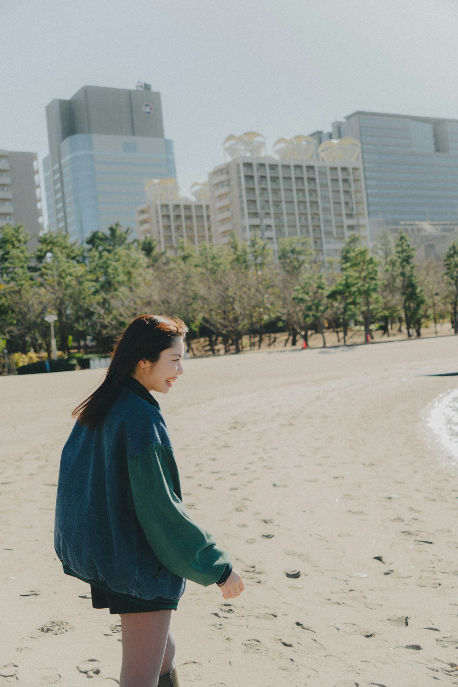 在海滩上走的女性和背景中的摩天大楼