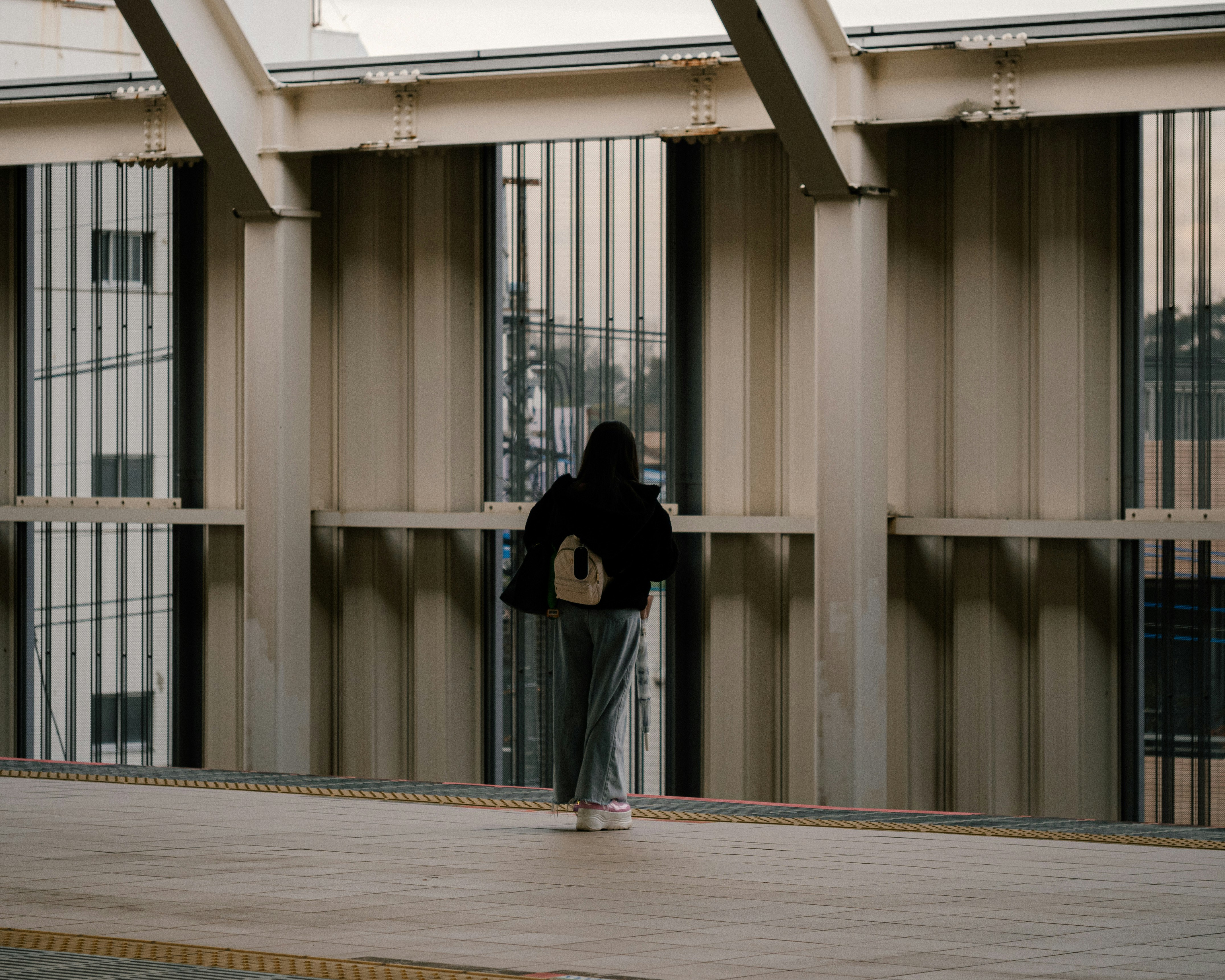 柱のある近代的な建物の前で歩く人物