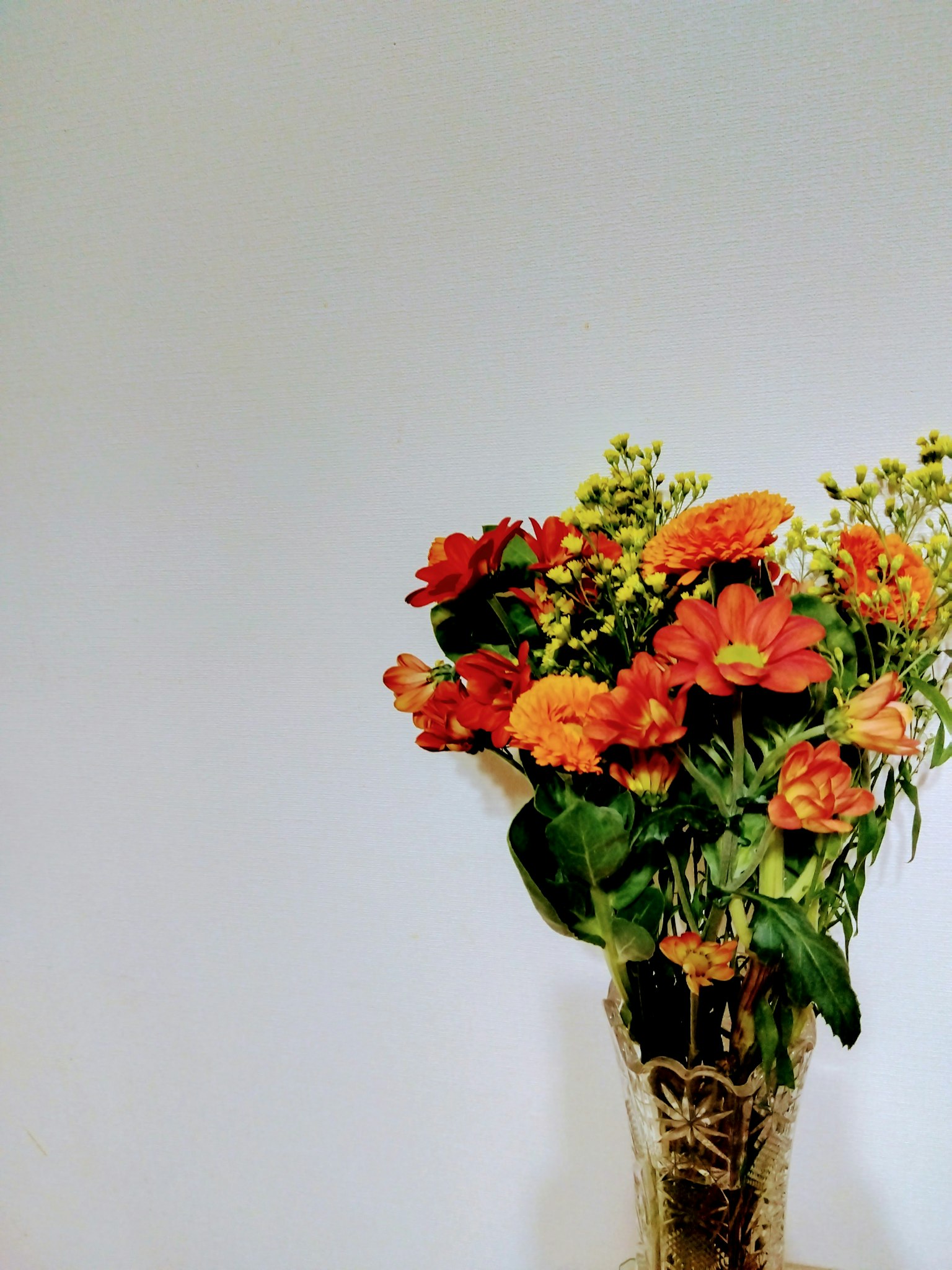 Un ramo de flores naranjas y rojas en un jarrón
