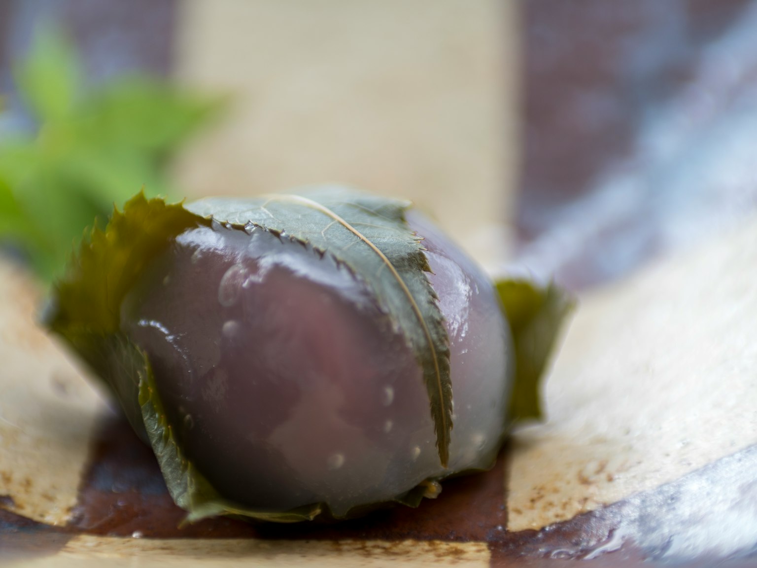 Eine schöne lila Kugel, eingewickelt in Blätter, die auf einer Holzoberfläche liegt