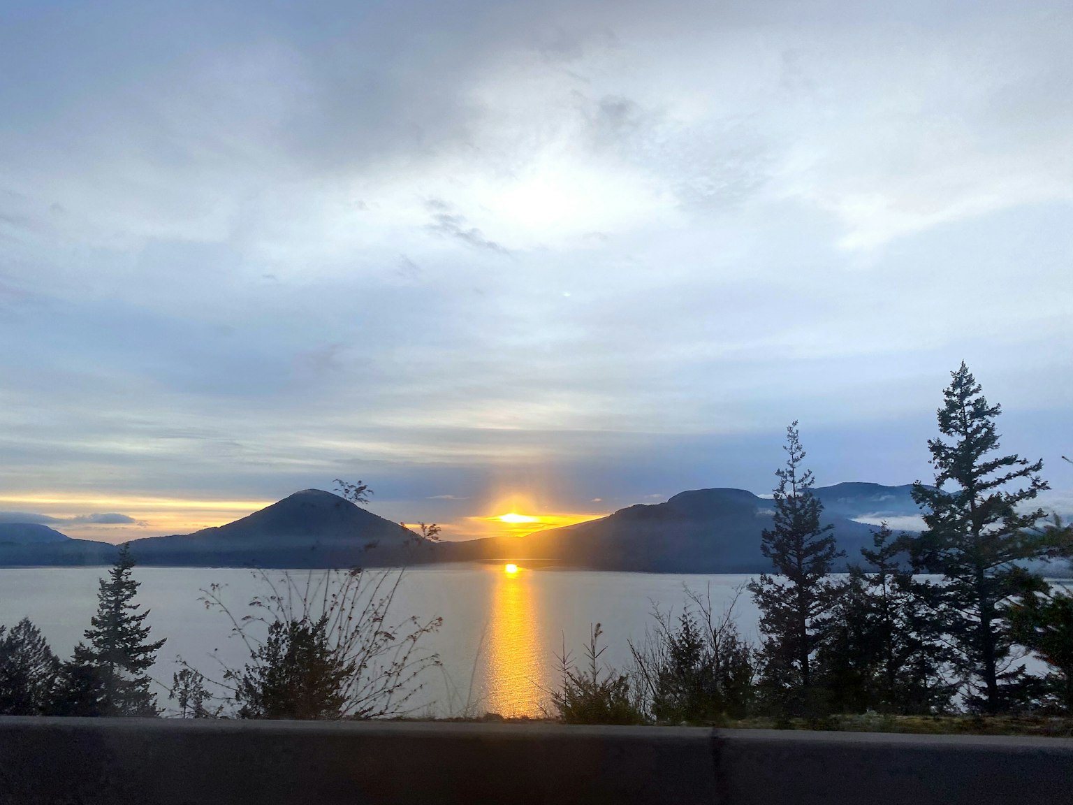 ทิวทัศน์ของพระอาทิตย์ตกเหนือทะเลสาบพร้อมภูเขา