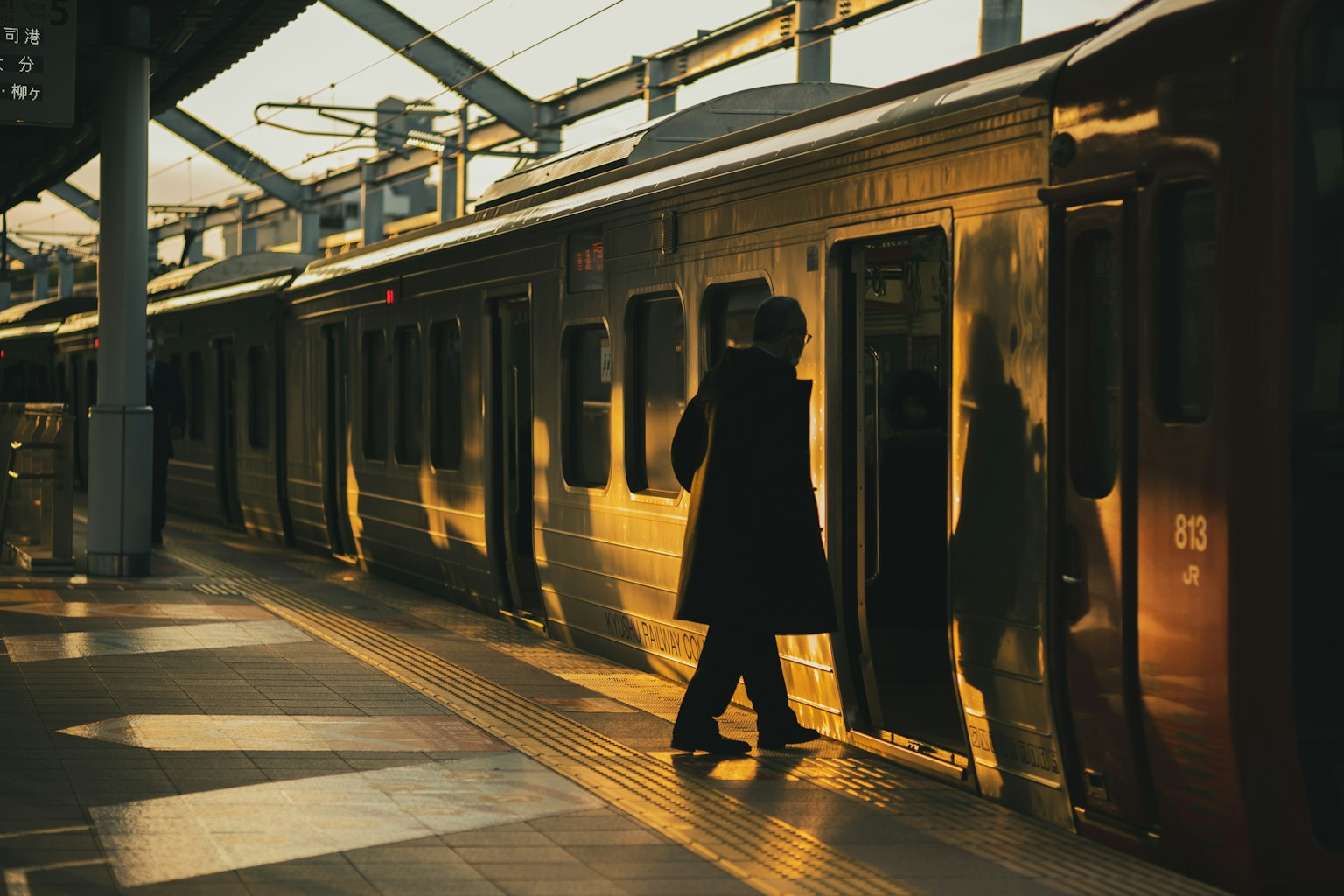 Personne s'approchant d'une porte de train à la lumière du coucher de soleil sur un quai de gare