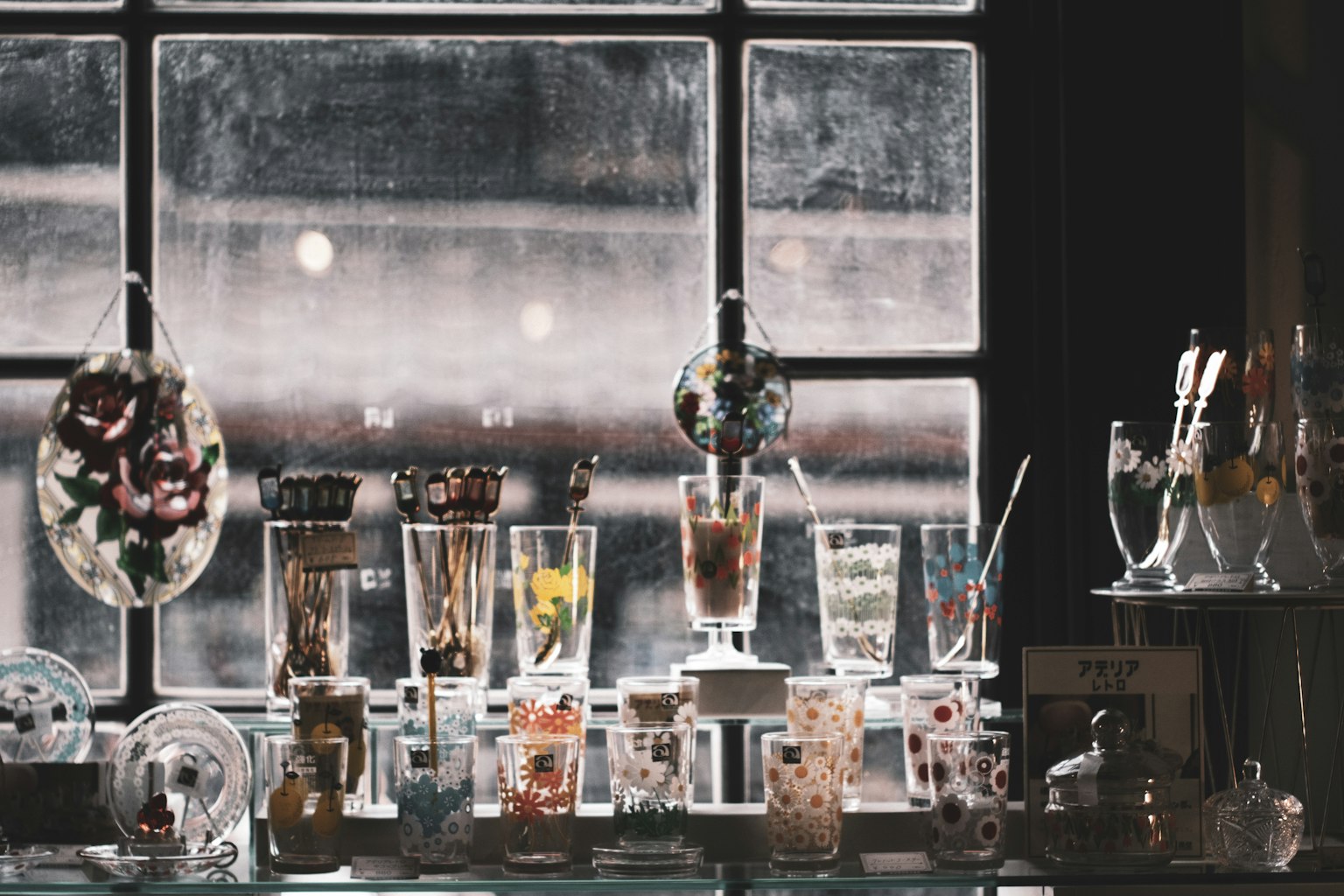 Verres à dessert colorés et boissons exposés devant une fenêtre