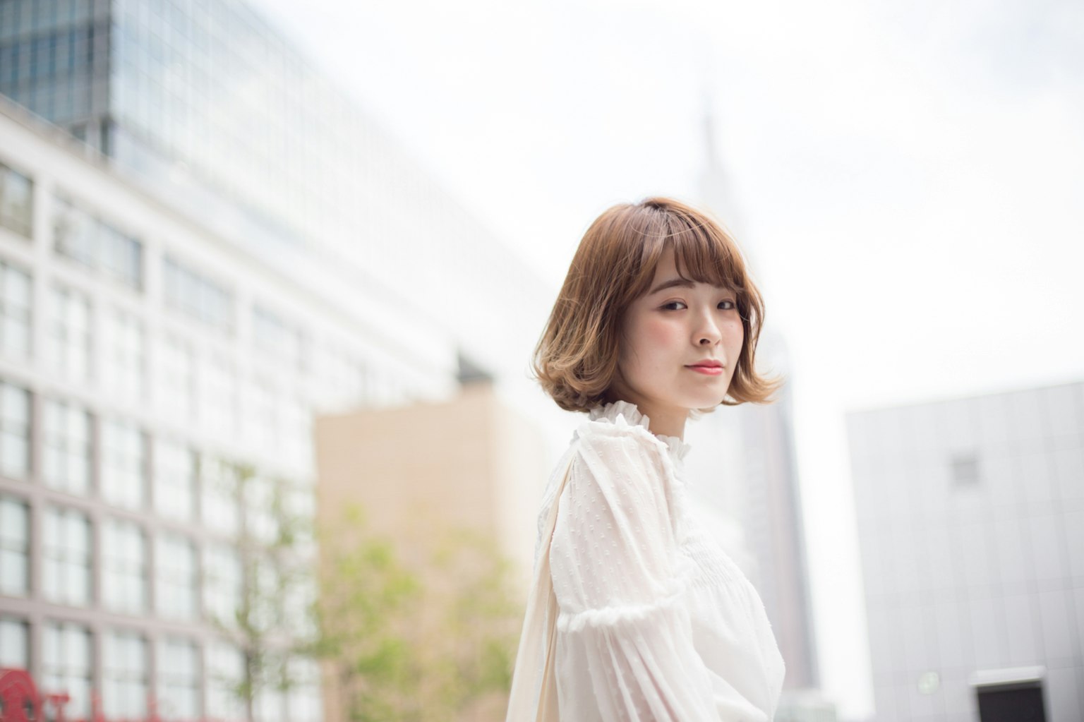 A woman wearing a white blouse smiling in an urban setting