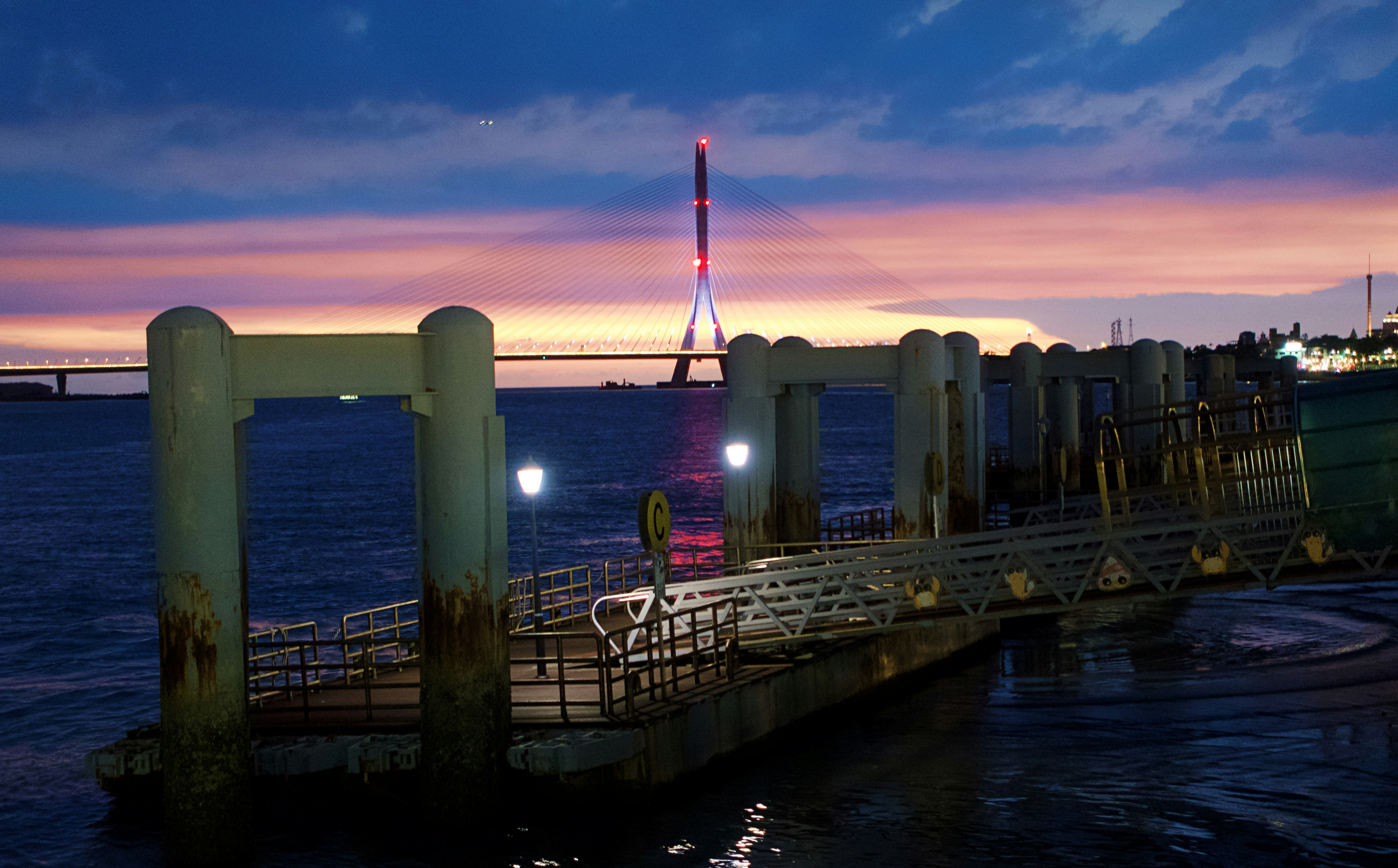 夕暮れの海沿いの桟橋と灯台のような塔