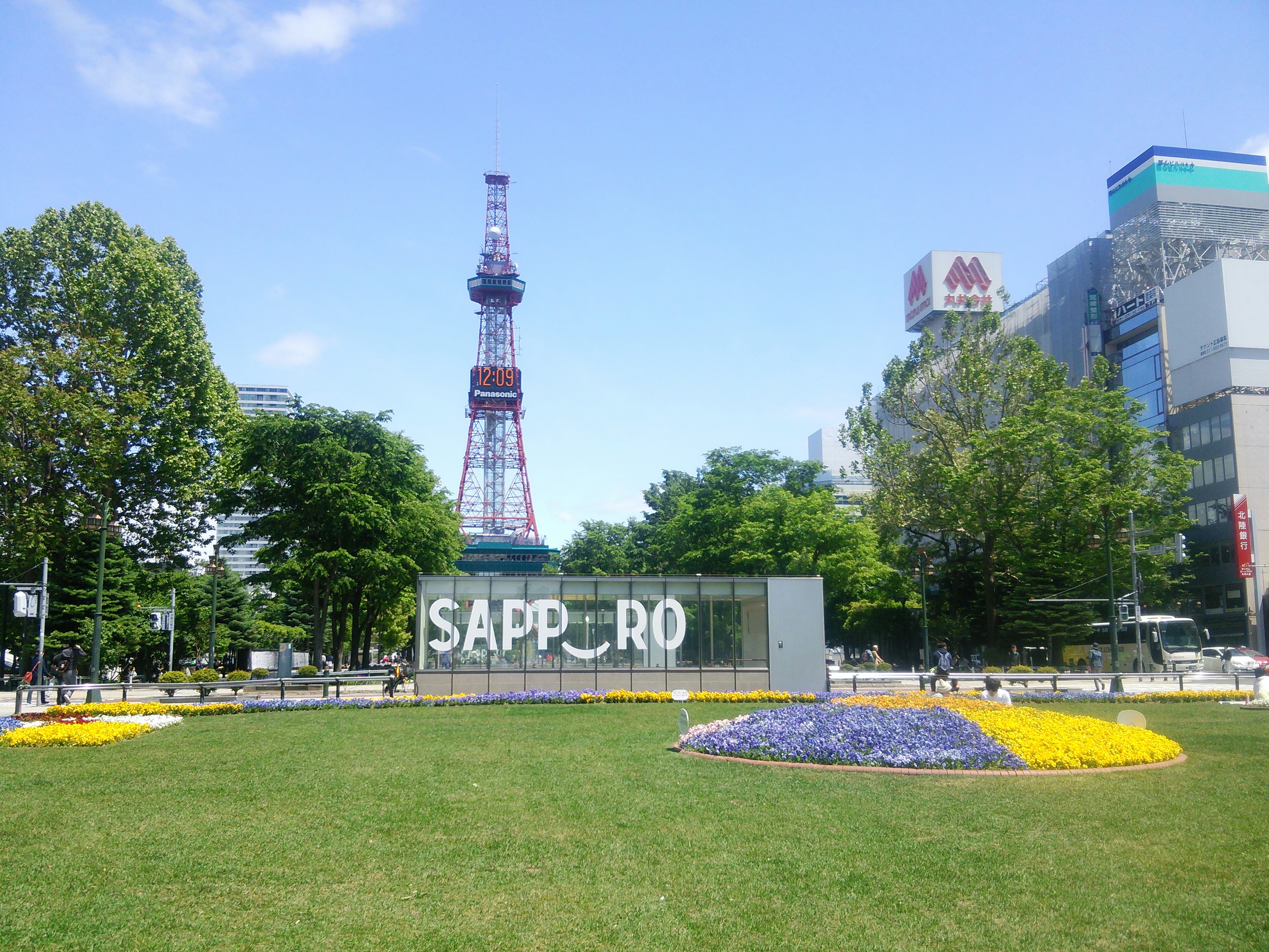 芝生の花壇とSAPPOROのモニュメント、テレビ塔が見える札幌の街並み