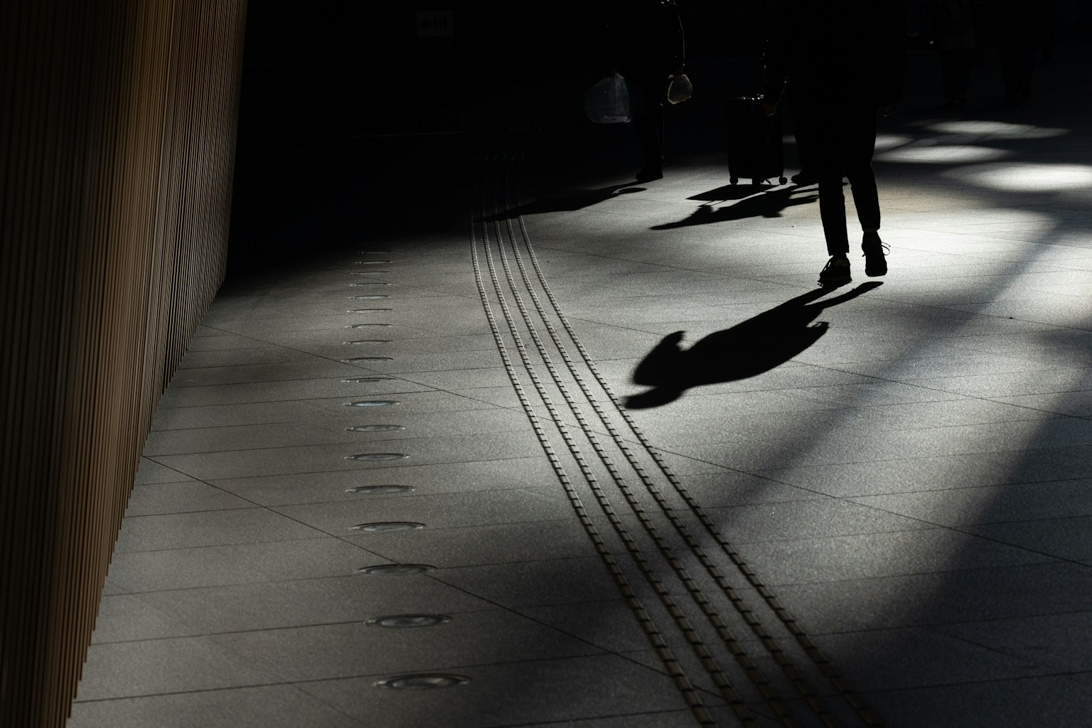 เงาของคนเดินอยู่บนทางเท้าที่มีเงา