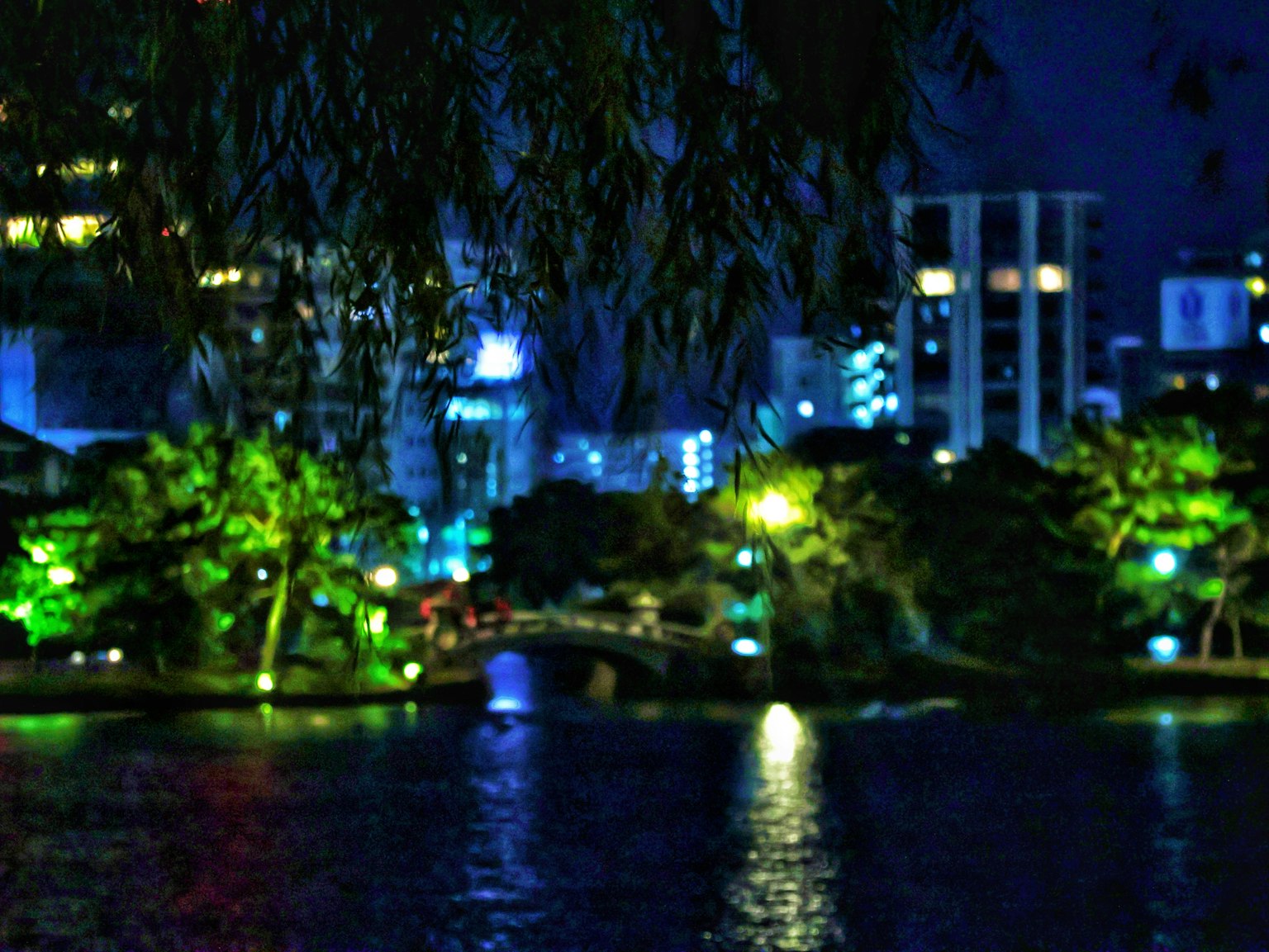 Paesaggio urbano notturno con alberi verdi e edifici illuminati di blu