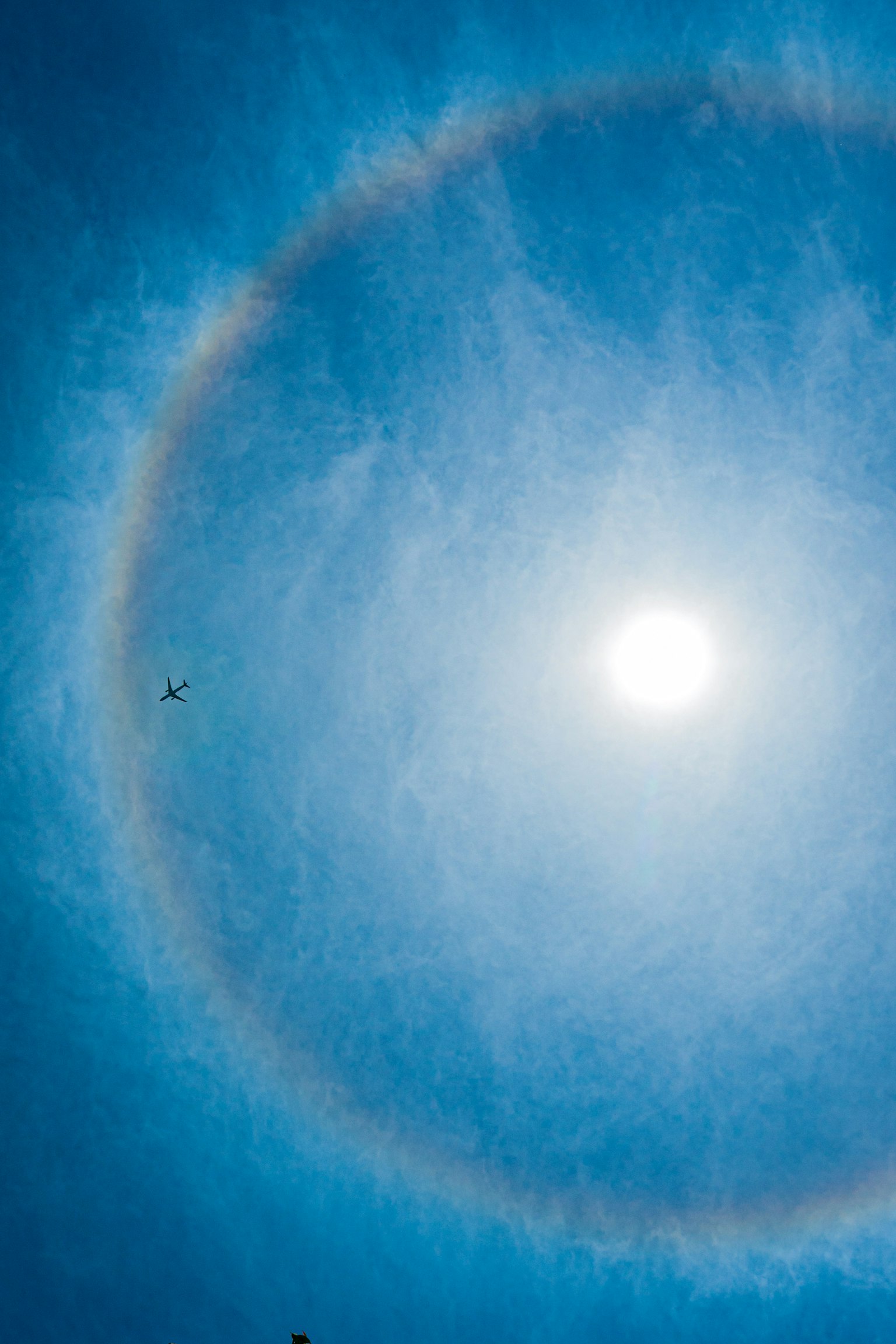 Un sole luminoso circondato da un alone arcobaleno in un cielo blu chiaro