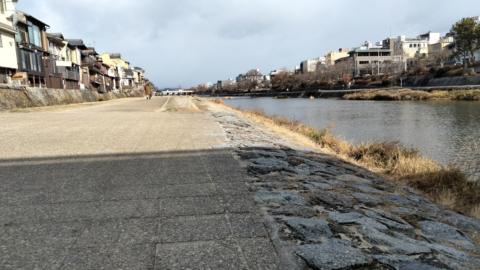 Sentiero pavimentato lungo un fiume con edifici sullo sfondo