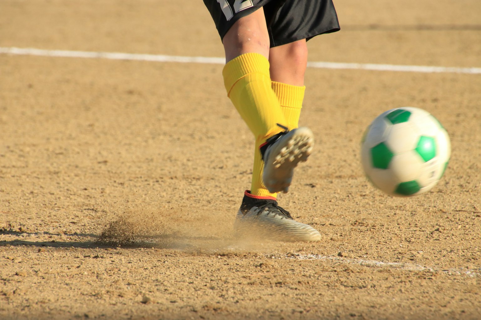 Un pied en mouvement frappant un ballon de football avec un design vert et blanc