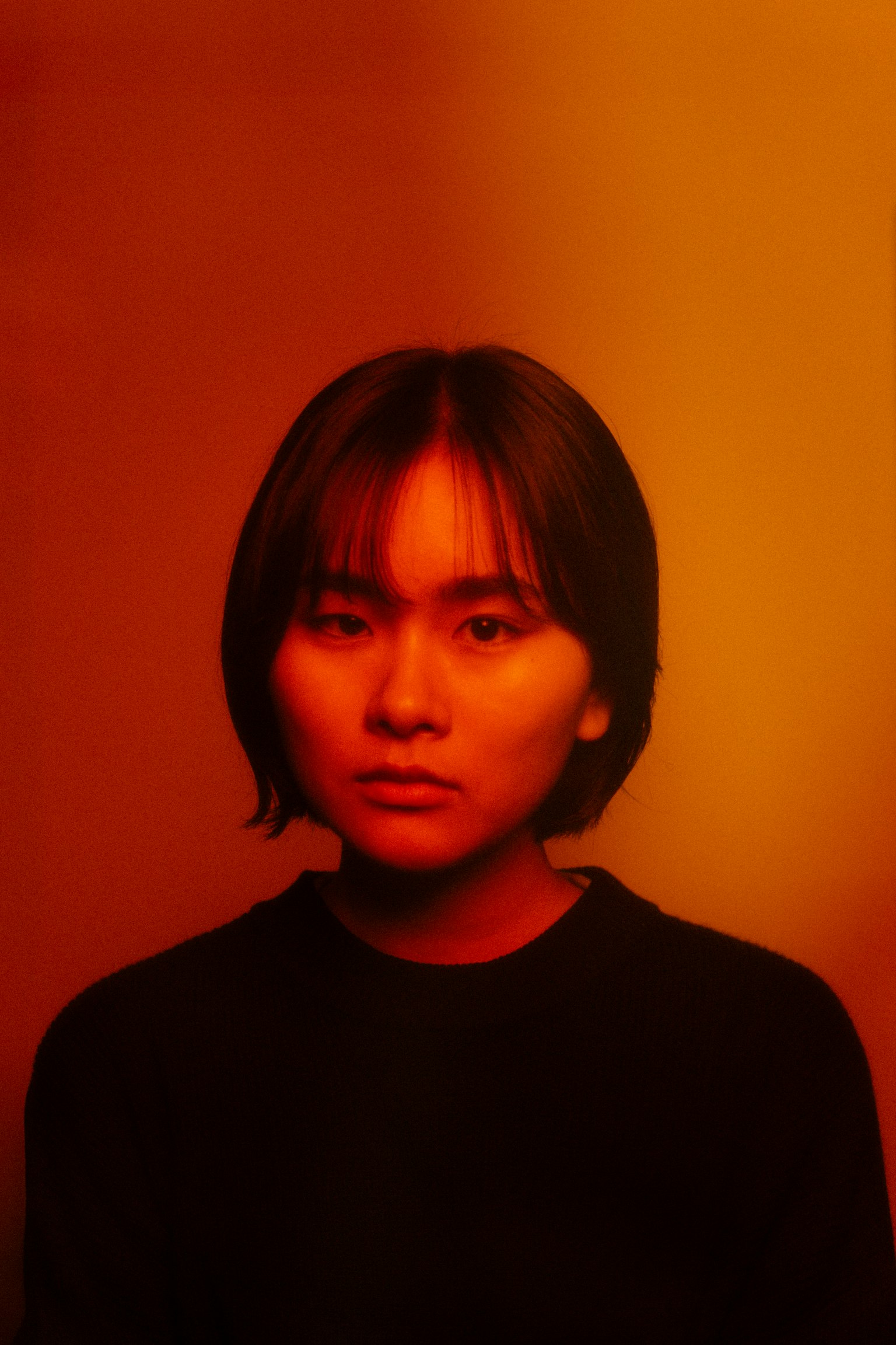Joven con cabello corto frente a un fondo naranja cálido