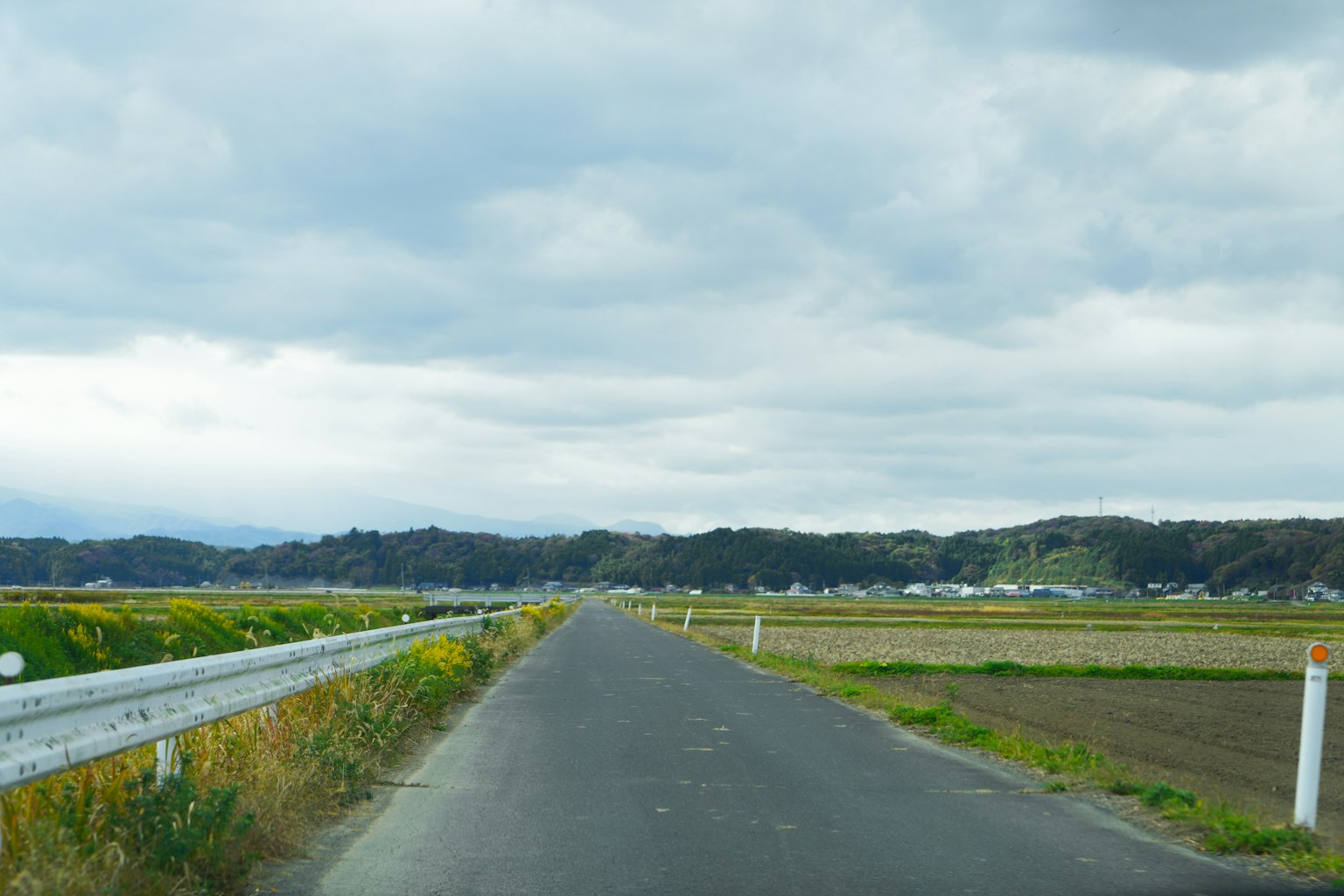 Route rurale et terres agricoles sous un ciel nuageux
