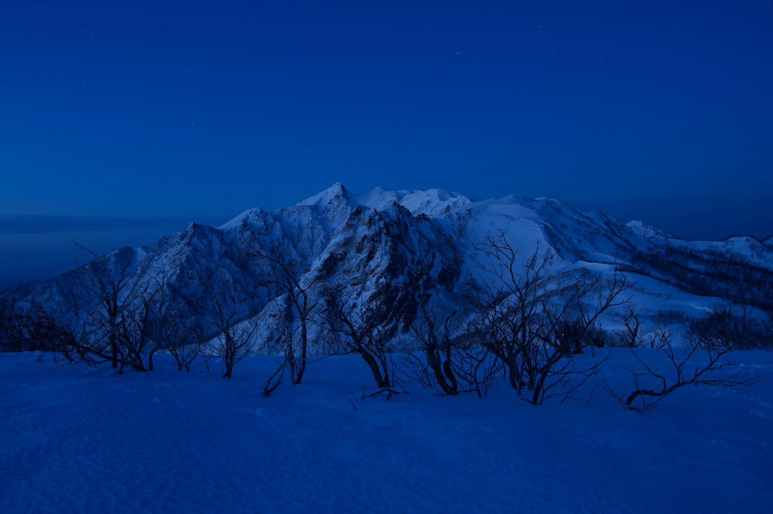 Montagnes enneigées sous un ciel bleu foncé