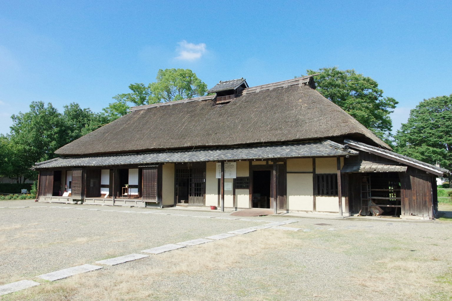 Rumah tradisional Jepang dengan atap jerami di halaman yang luas