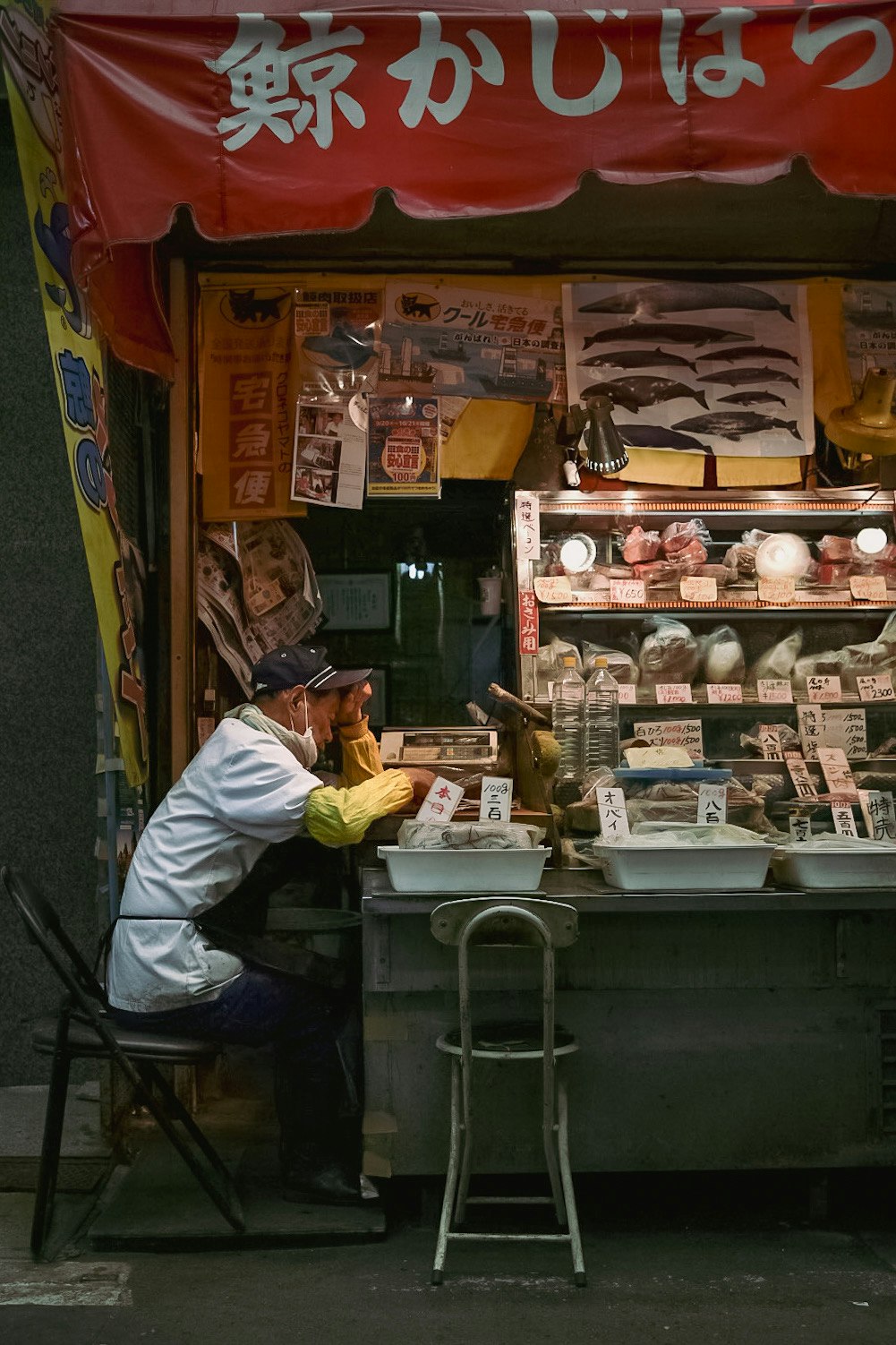 街頭攤位裡擺著鯨魚乾製品，男子在操作