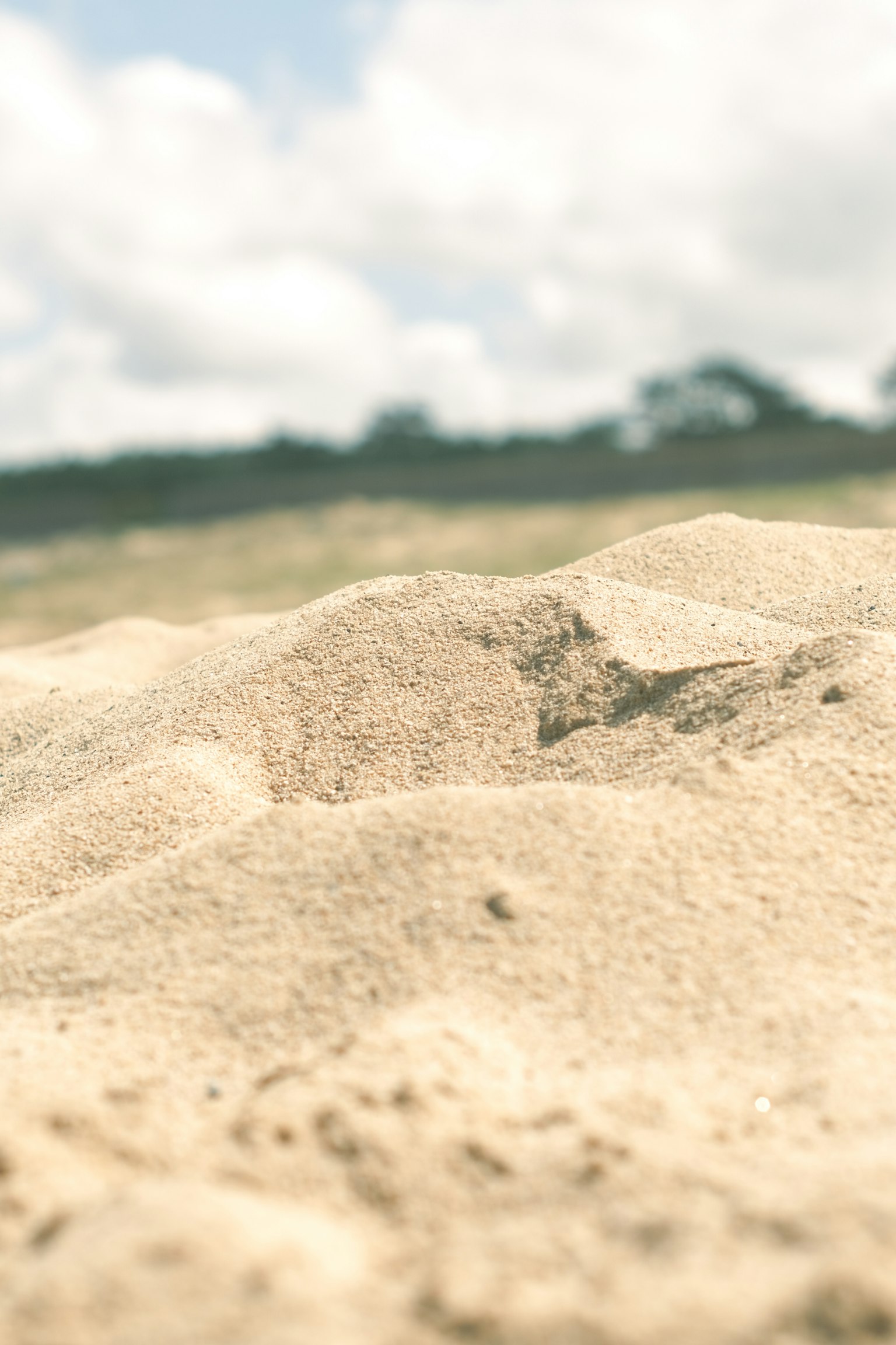 Blurred view of sandy terrain with clouds in the background