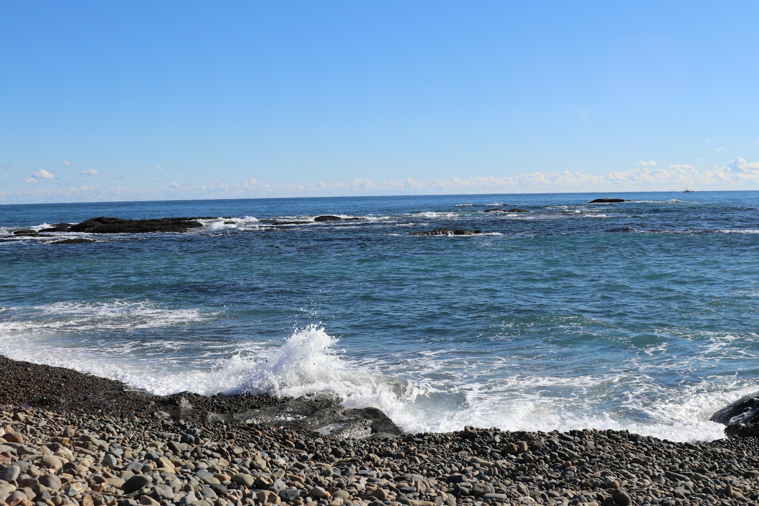 Vue panoramique d'une plage rocheuse avec un océan bleu et des vagues blanches