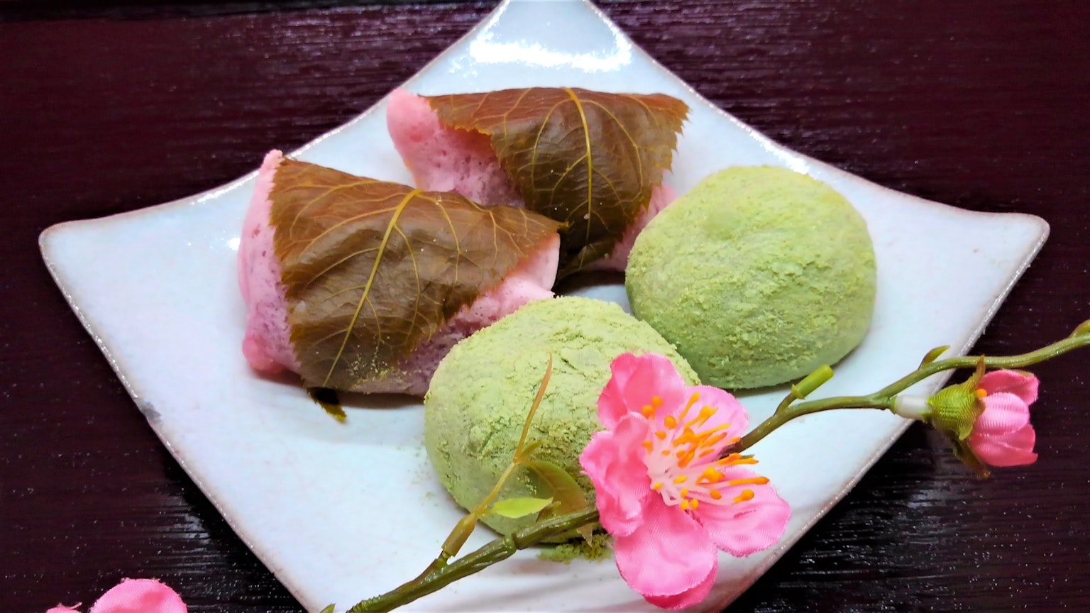 Dulces japoneses envueltos en hojas de cerezo y bolitas de matcha en un plato