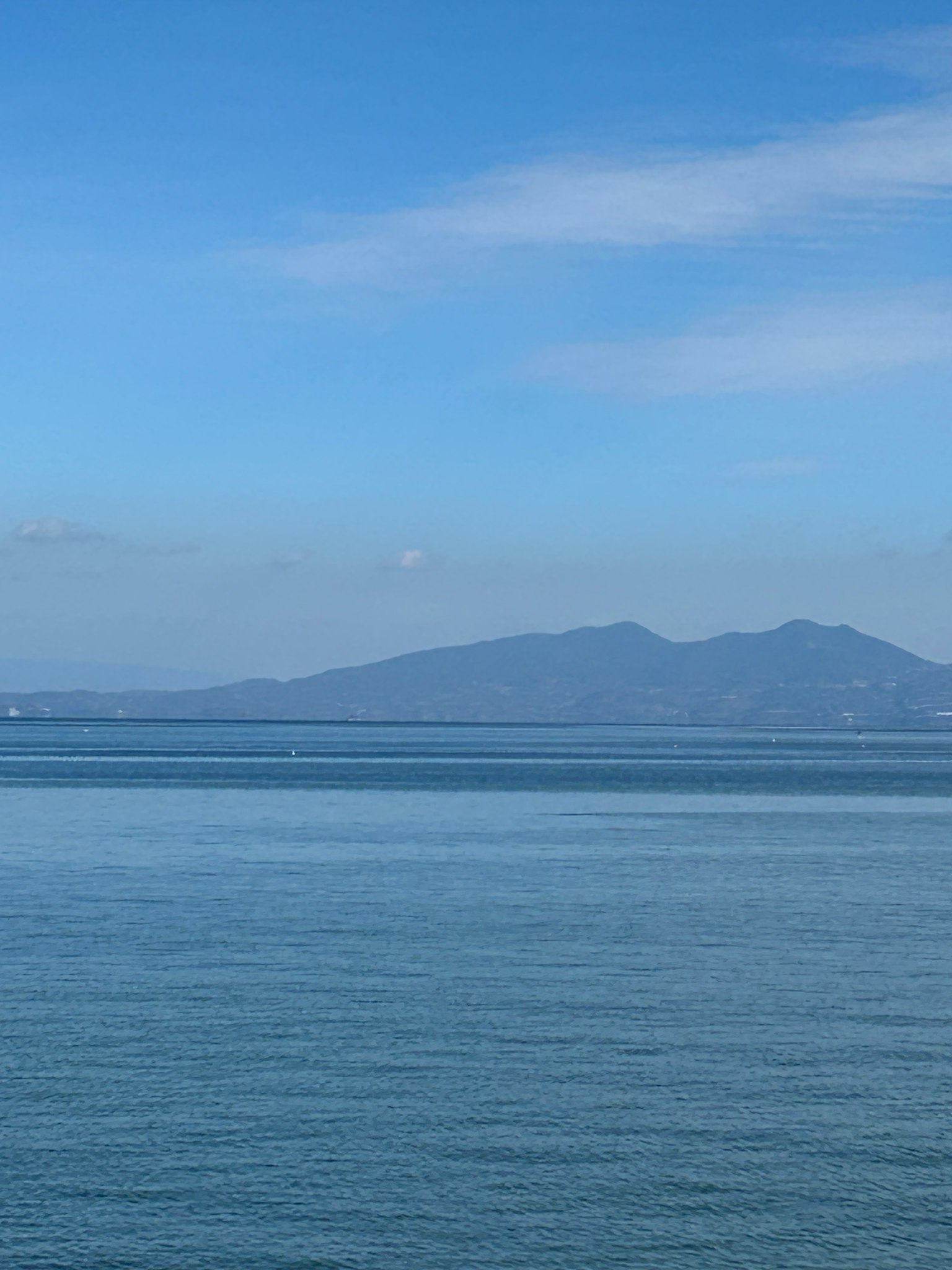 平静的蓝色海洋和天空风景，远处有山