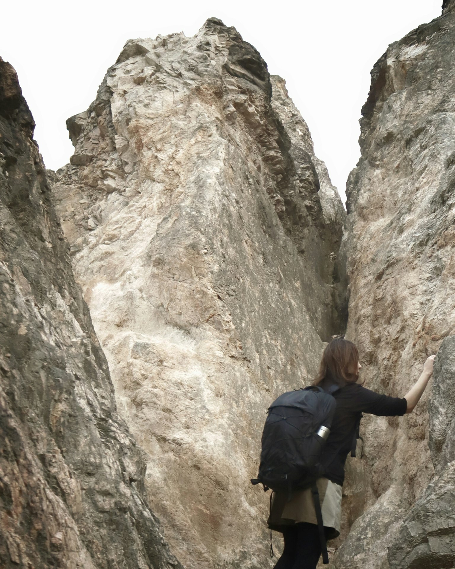 Person klettert zwischen großen Felsen