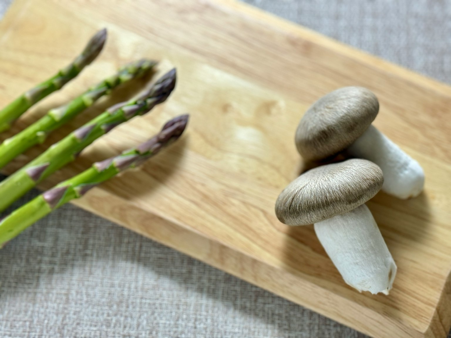 Asparagus dan jamur disusun di atas papan kayu