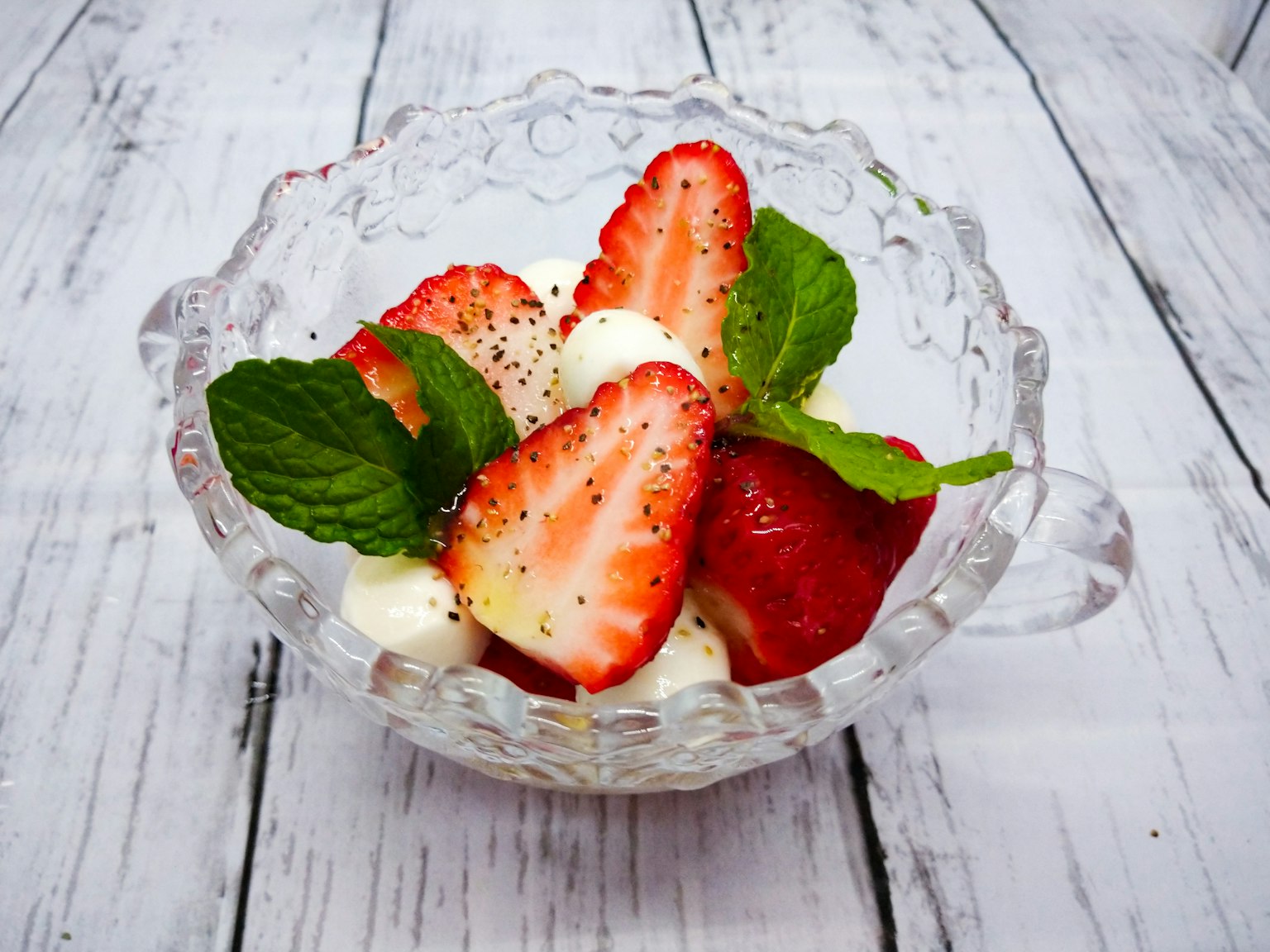 Ciotola di fragole e foglie di menta con panna montata