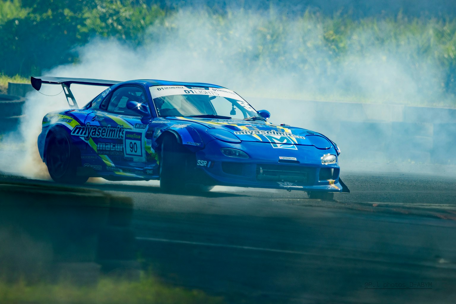 Mobil sport biru meluncur dengan asap di lintasan balap