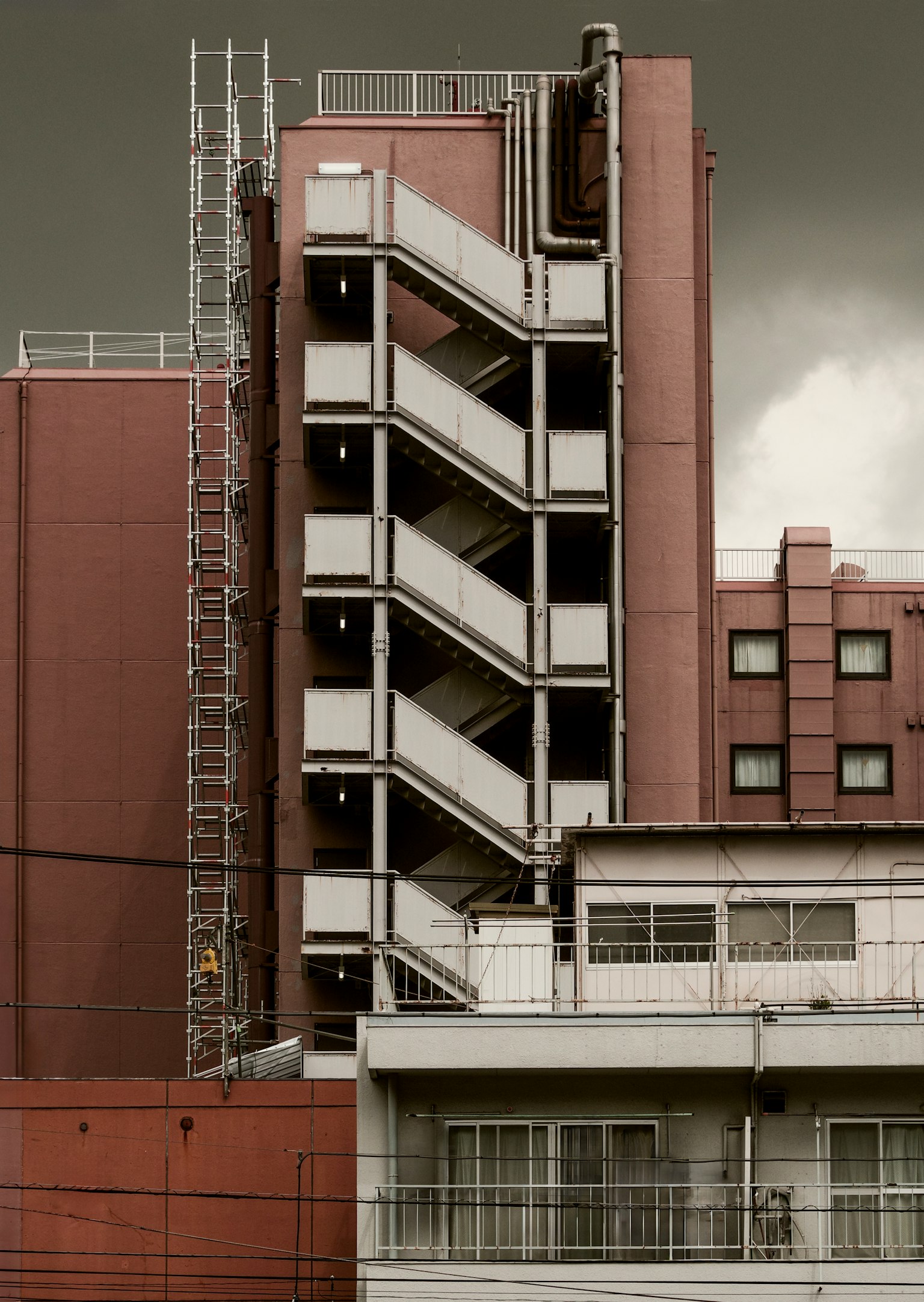 Escena urbana con un edificio rojo y una escalera exterior