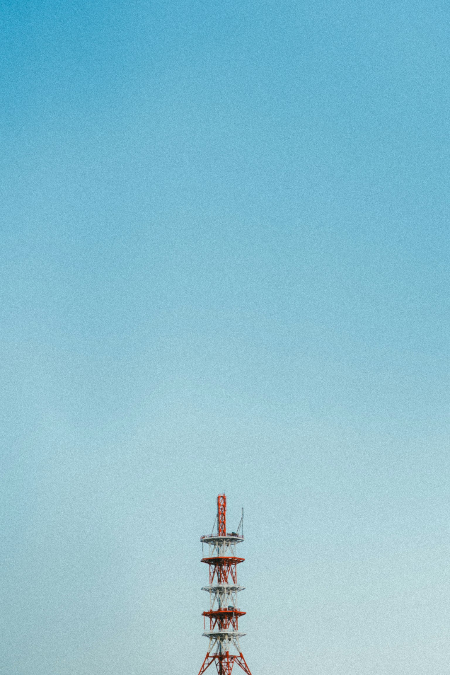 Torre di comunicazione rossa contro un cielo blu chiaro