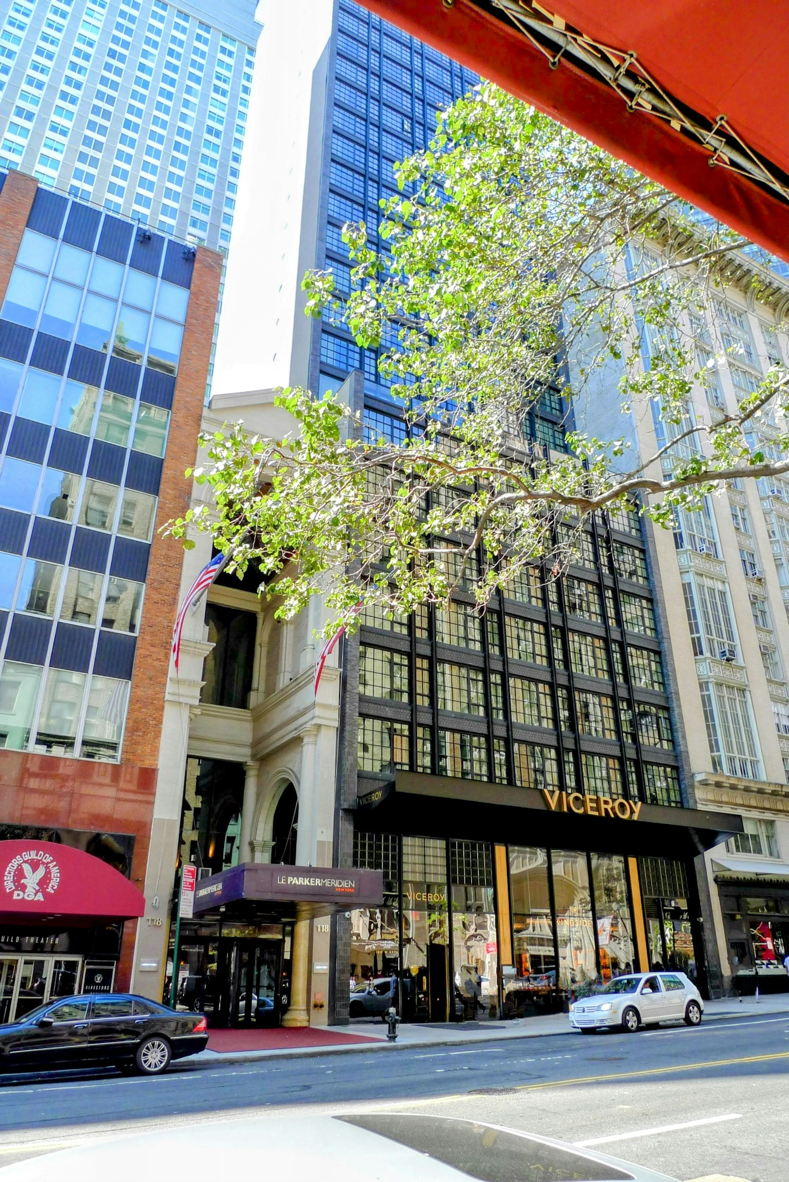 Street view featuring Victoria's store with tall buildings and green trees