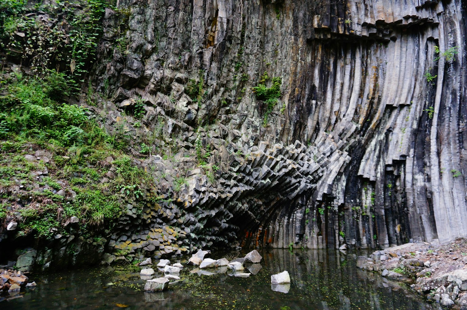 Naturlandschaft mit säulenförmigen Basaltformationen und Spiegelungen im Wasser