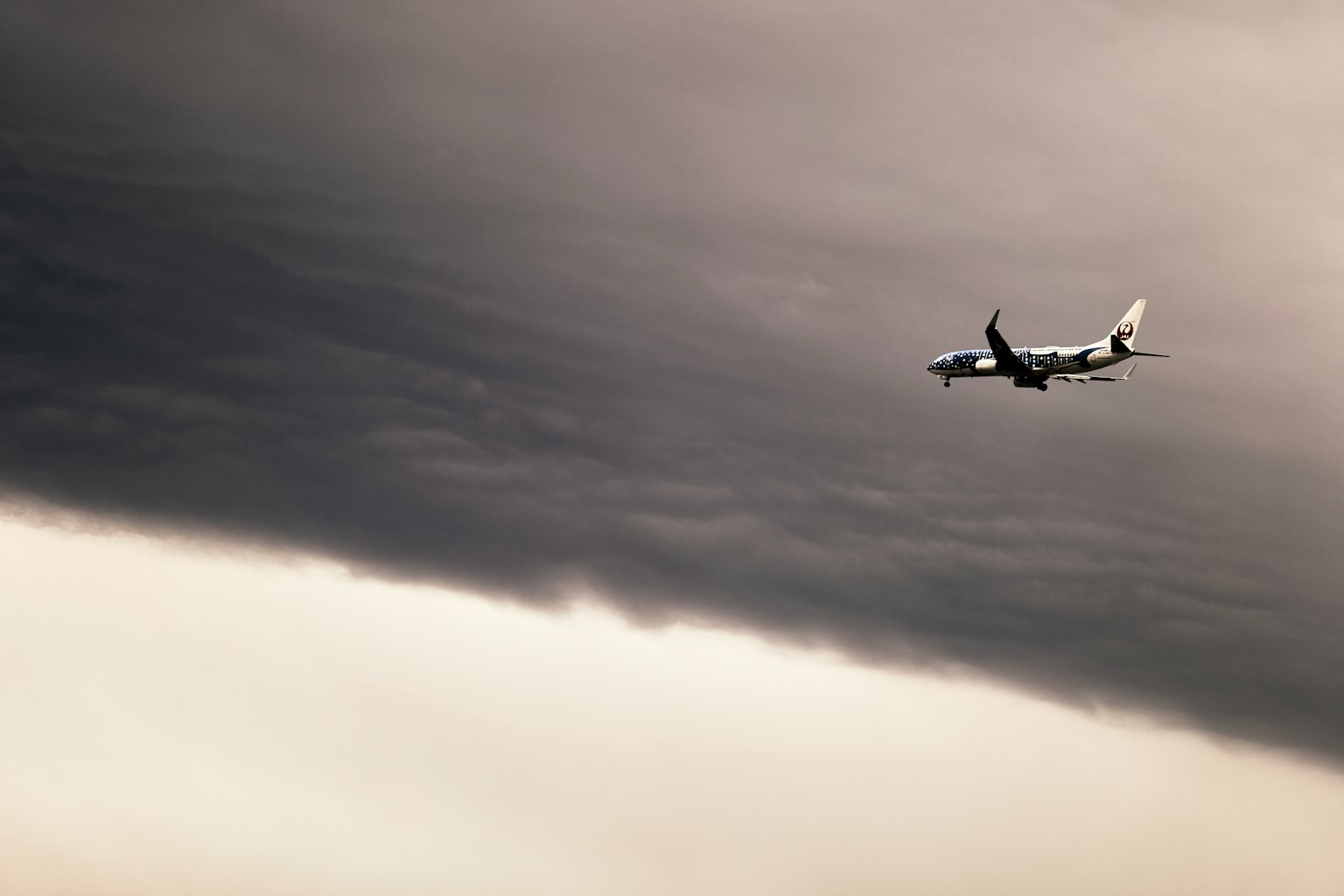 Silhouette di un aereo che vola tra nuvole scure