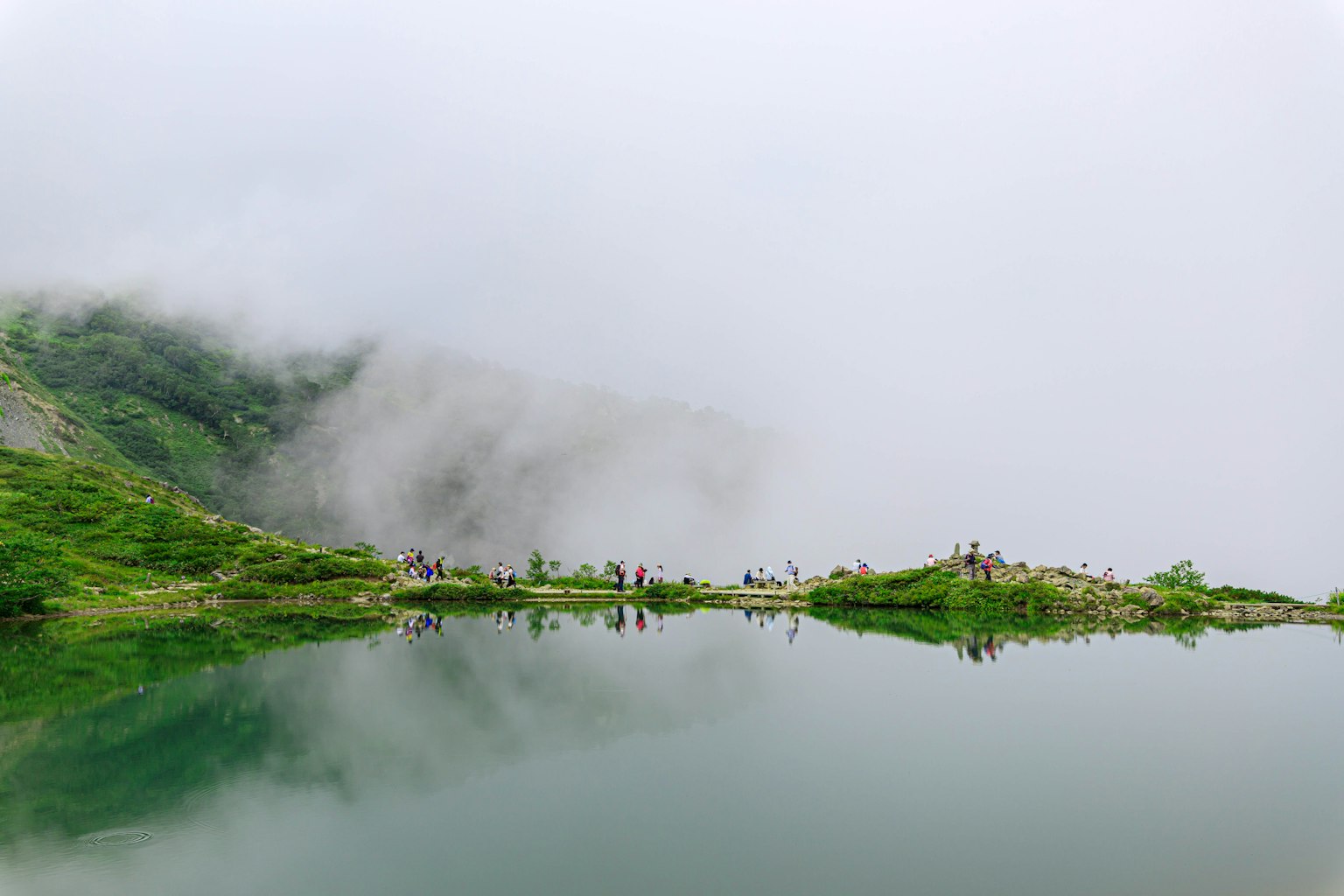 雾气弥漫的山景与宁静的湖泊，远处有人影