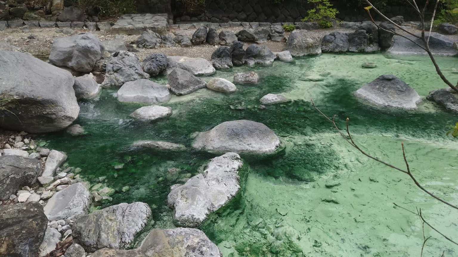 Natürliche Landschaft mit grünlichem Wasser und großen verstreuten Felsen