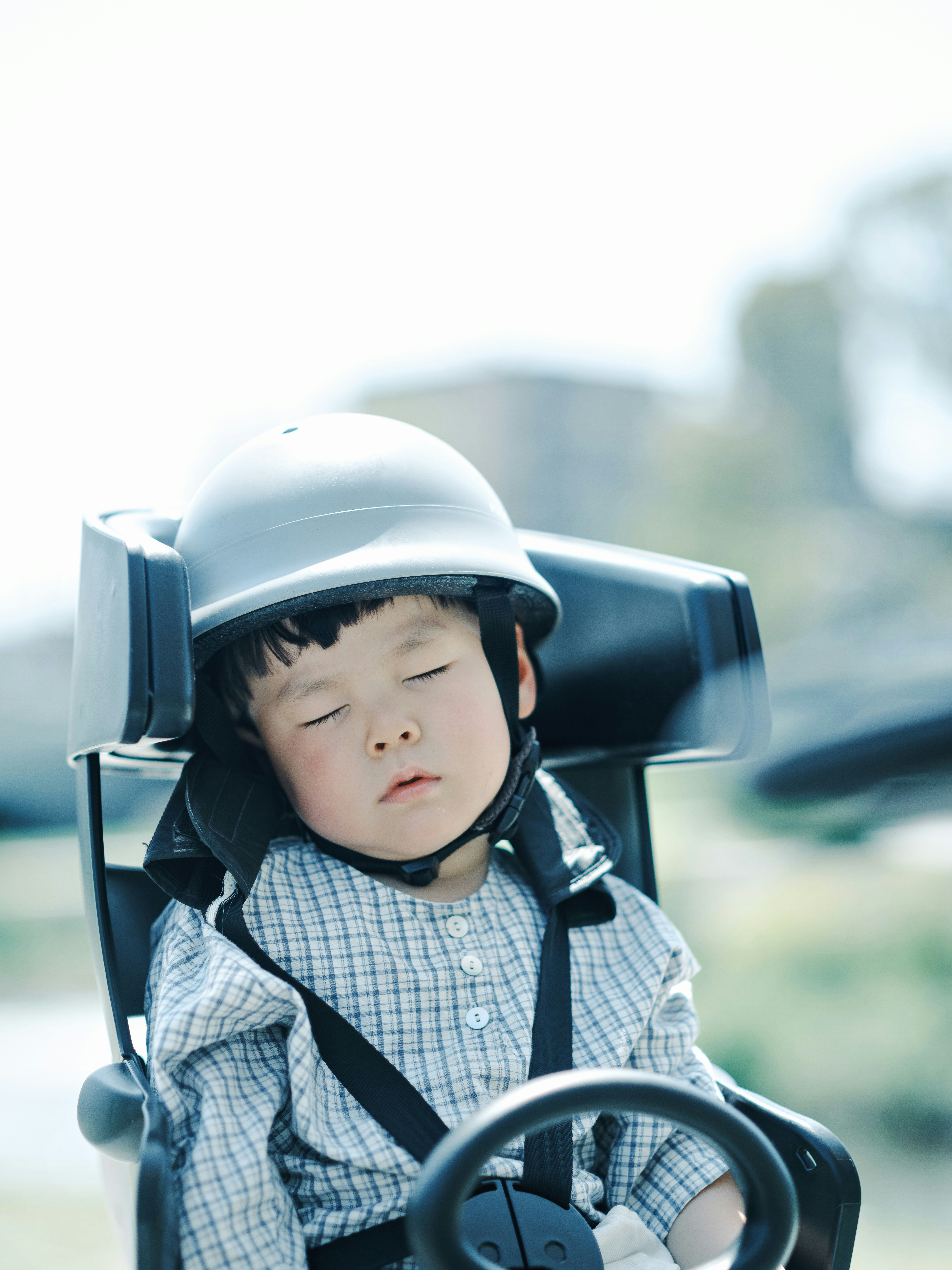 toddler wearing a helmet riding in a stroller
