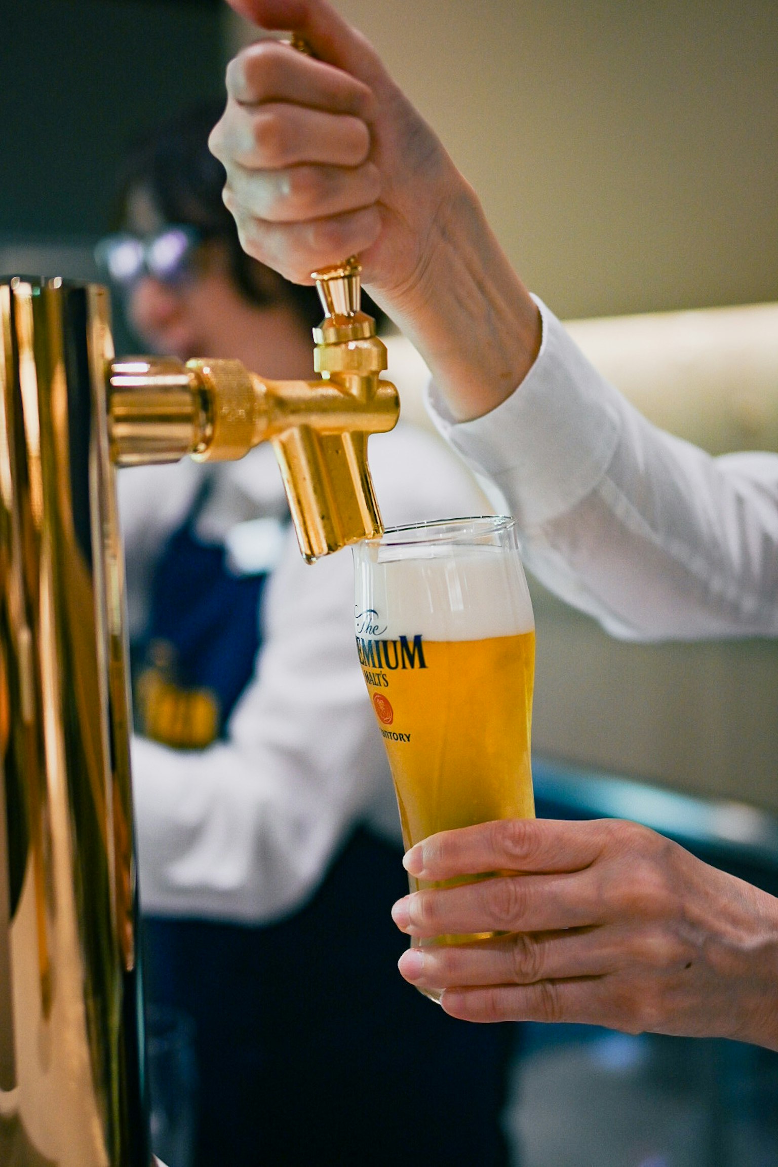 Gros plan d'une main versant de la bière d'un robinet doré dans un verre