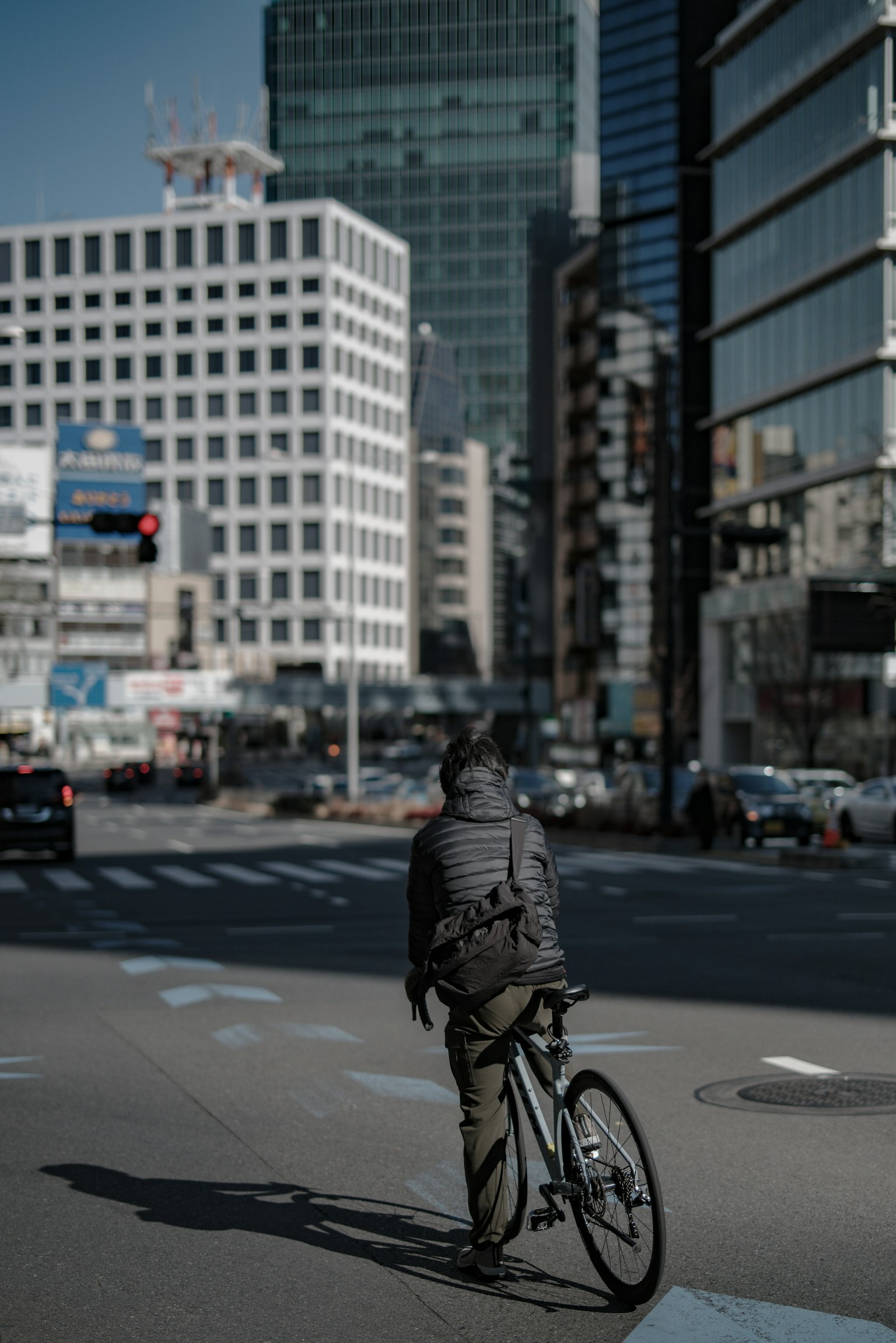 一个人在城市交叉口骑自行车，背景是摩天大楼