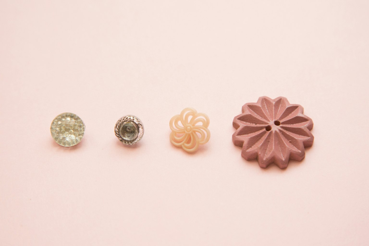 Quatre boutons au design unique sur un fond rose