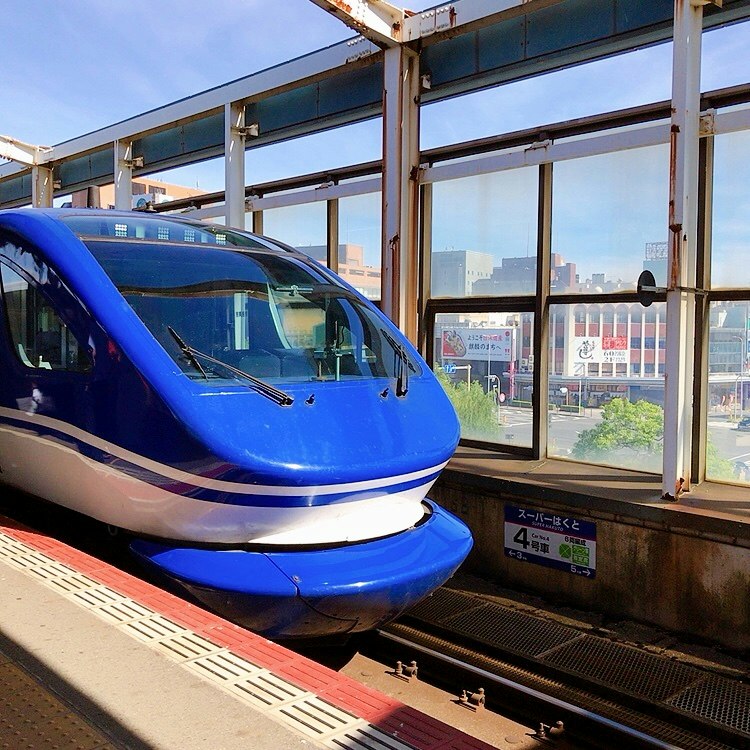 ガラス張りの駅ホームに停車する青い新幹線