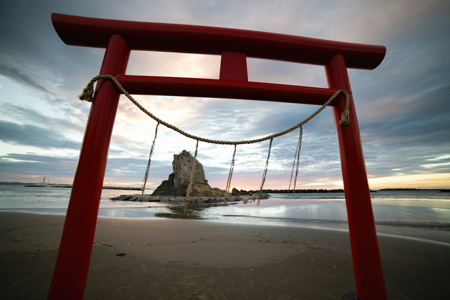 紅色鳥居和背景中的岩石島嶼在日落時分