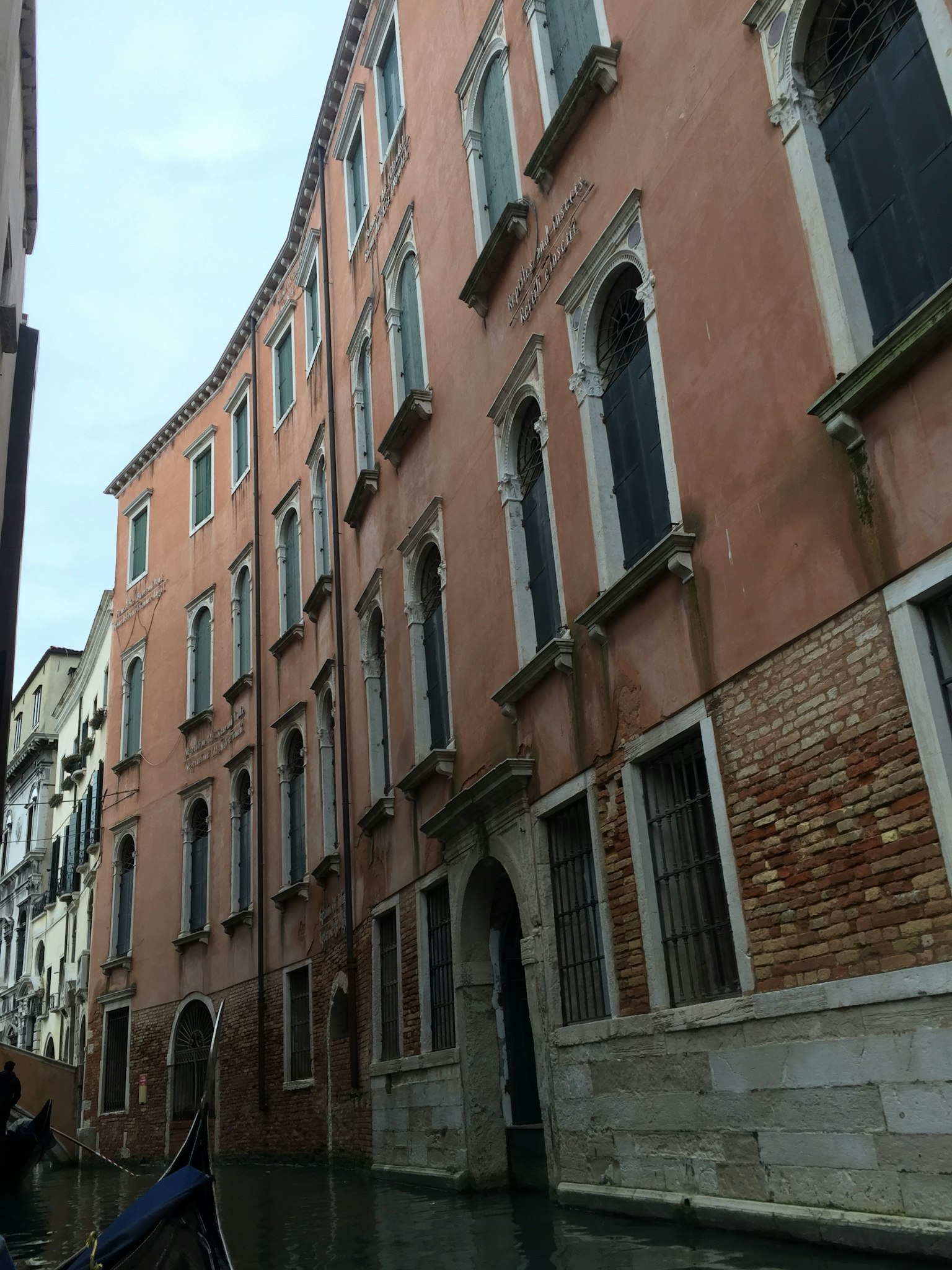Une scène pittoresque de bâtiments roses le long d'un canal à Venise avec des fenêtres uniques